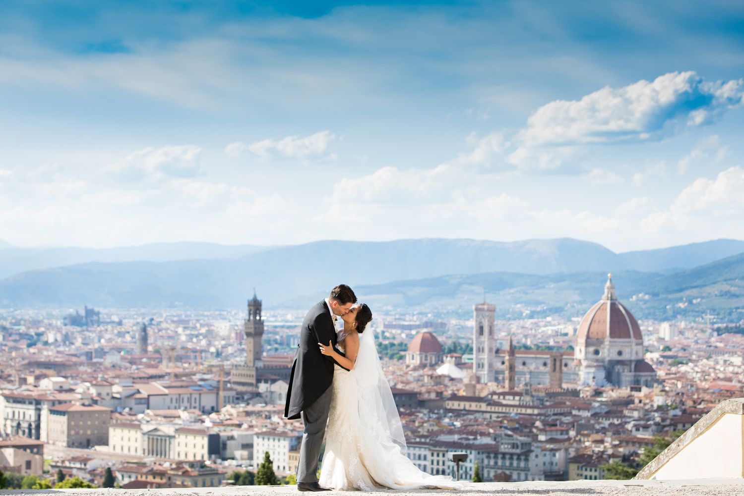 A couple shares a romantic moment overlooking the iconic Florence cityscape with the Duomo cathedral visible in the background.