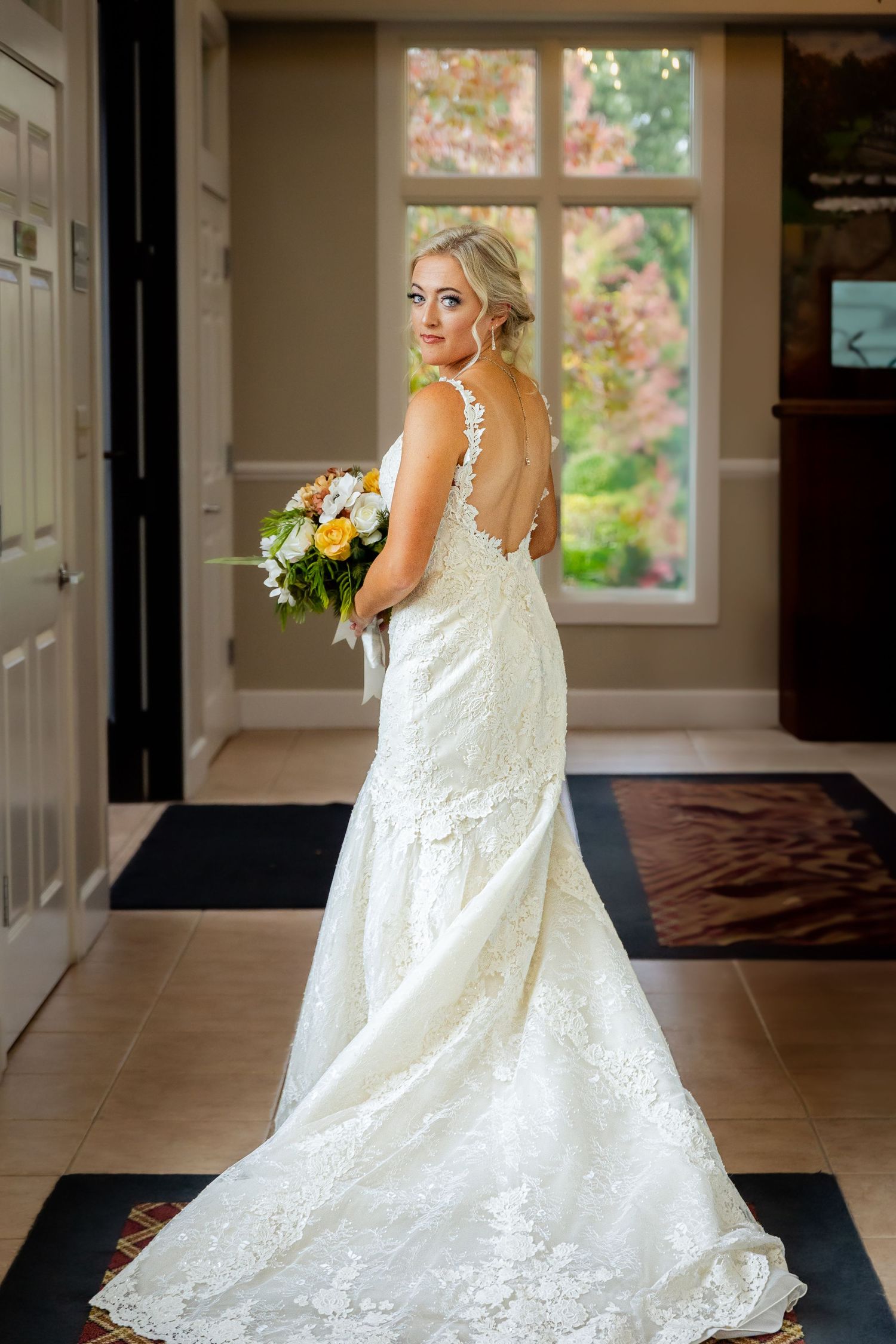 A bride in her wedding dress holding a bouquet of flowers looking at the camera in a wedding venue