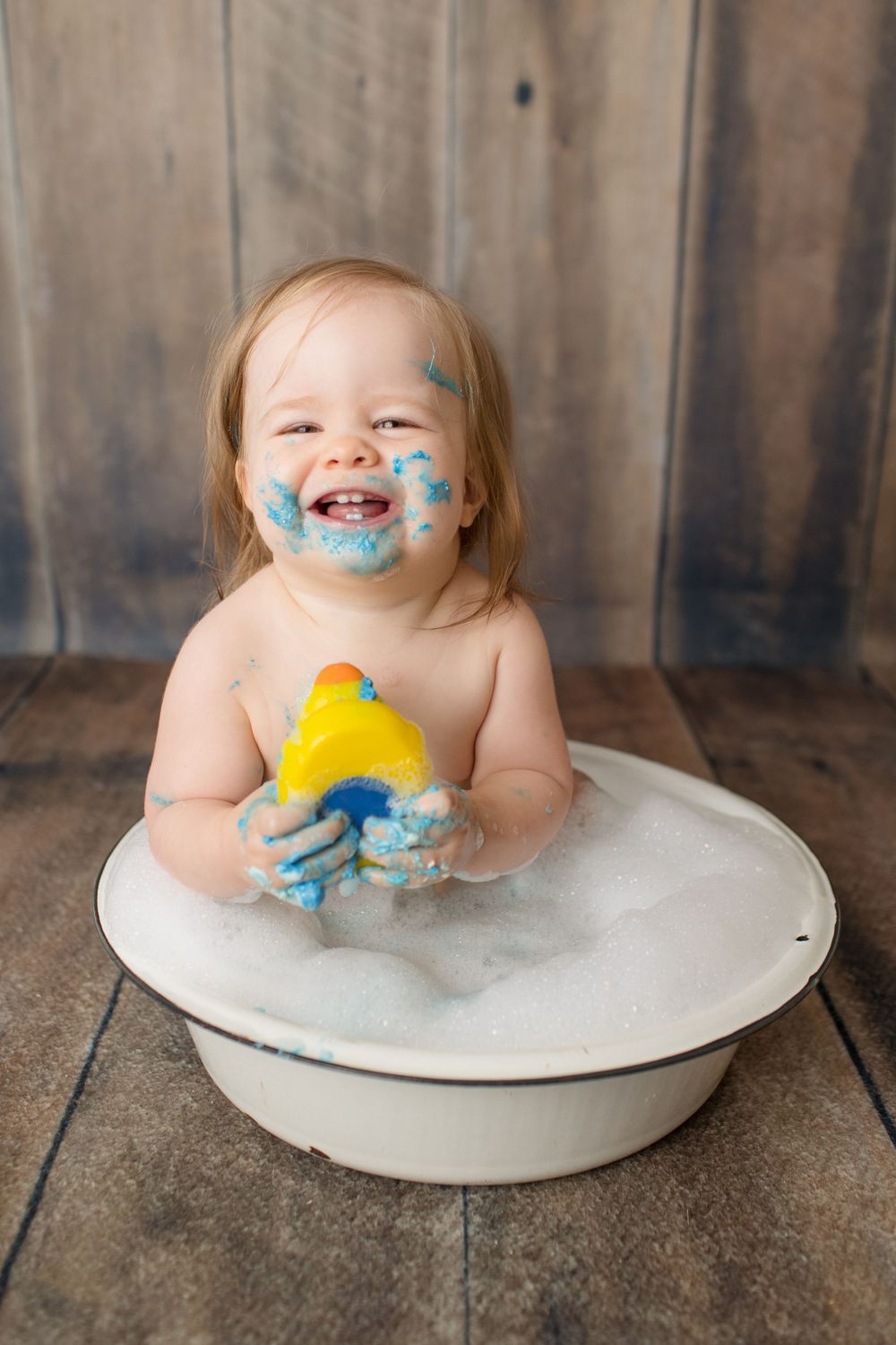 Playful bath time with rubber duck and bubbles against rustic wooden backdrop.