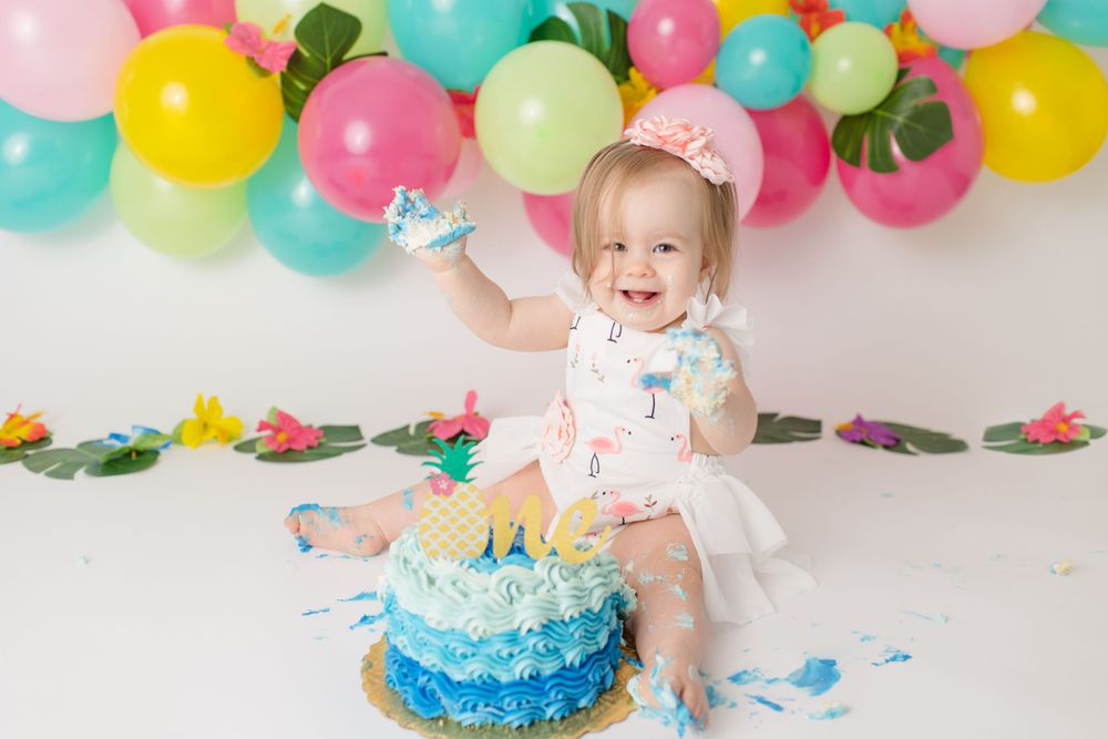Joyful cake smash session with colorful balloons and blue ombre cake.