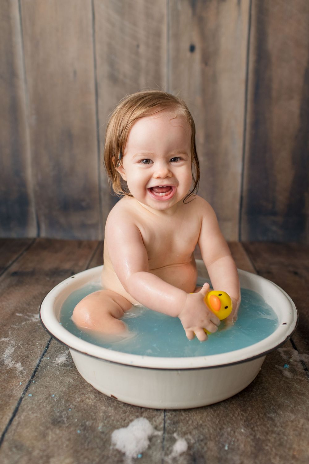 Happy bath time moment with yellow duck toy and blue water.