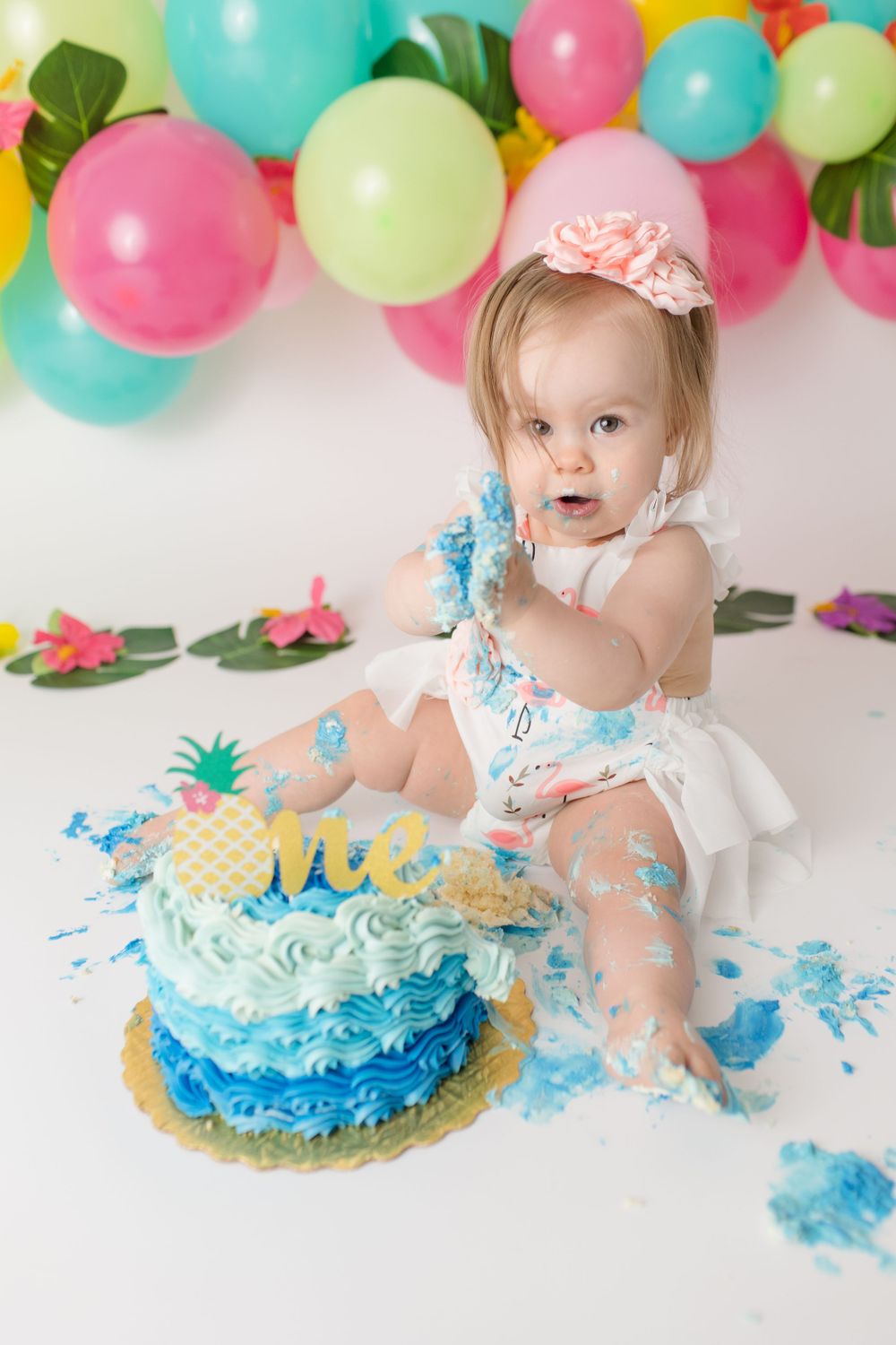 Blue ombre cake smash with pineapple decoration and pink balloons.