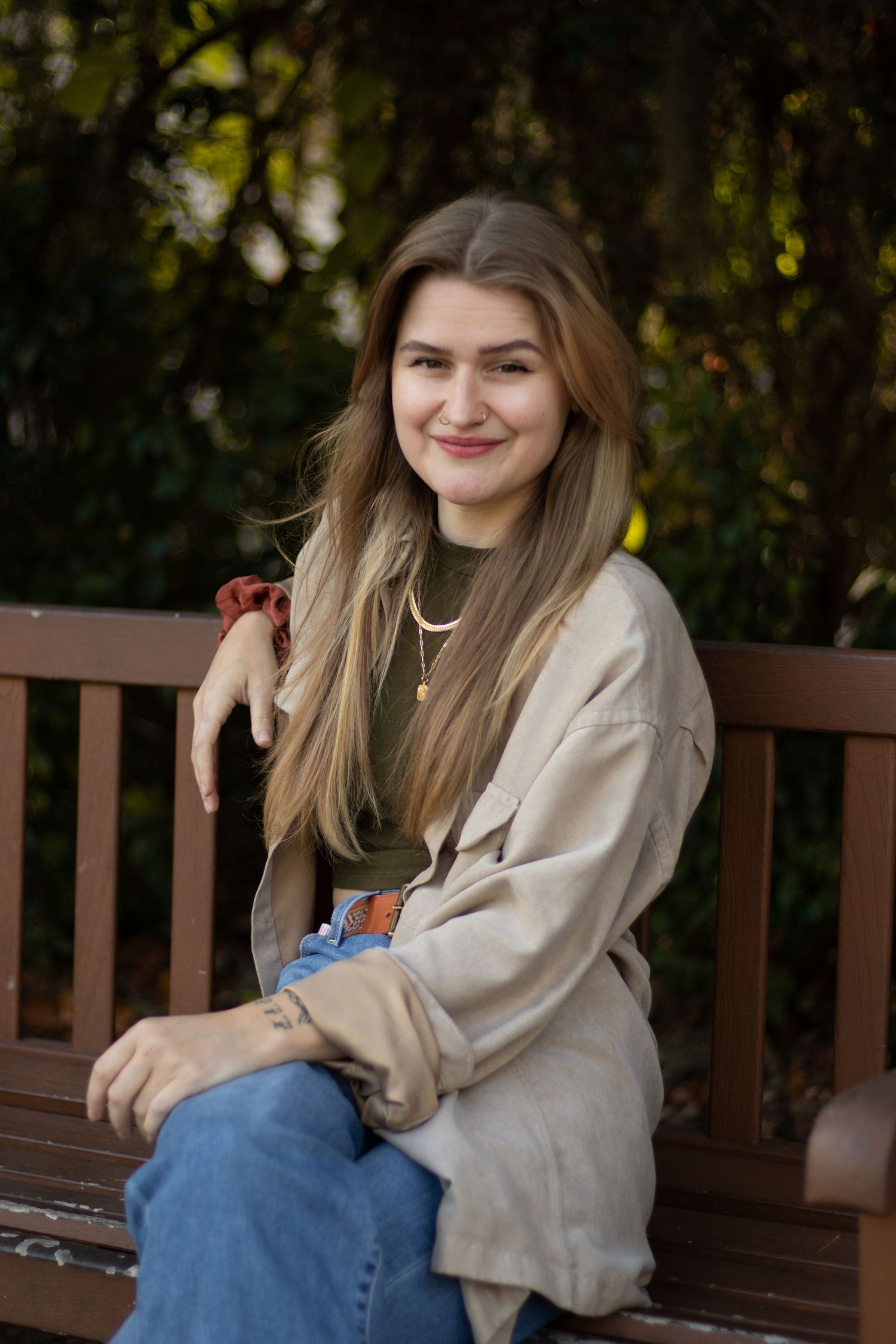 Portrait photo of fashionably dressed woman with long brown hair and nose piercings