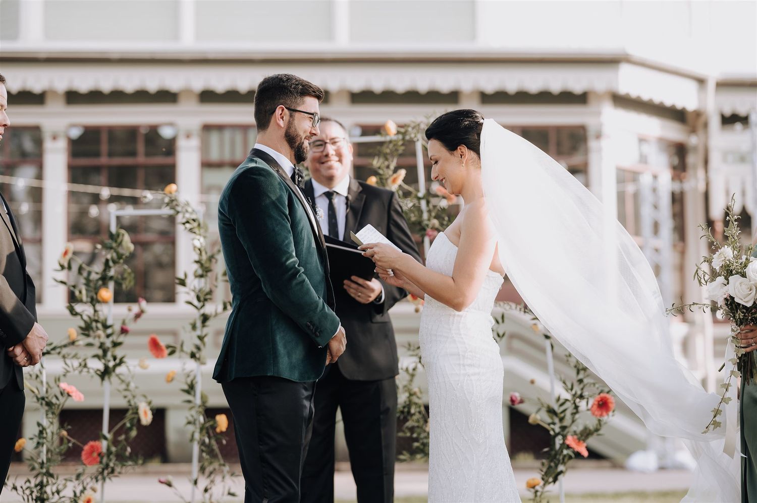 Intimate outdoor wedding ceremony moment in front of a white Spanish-style building.