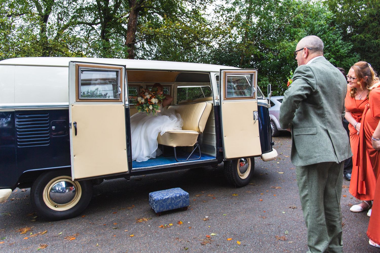 A classic VW van serves as wedding transport with guests gathered around.