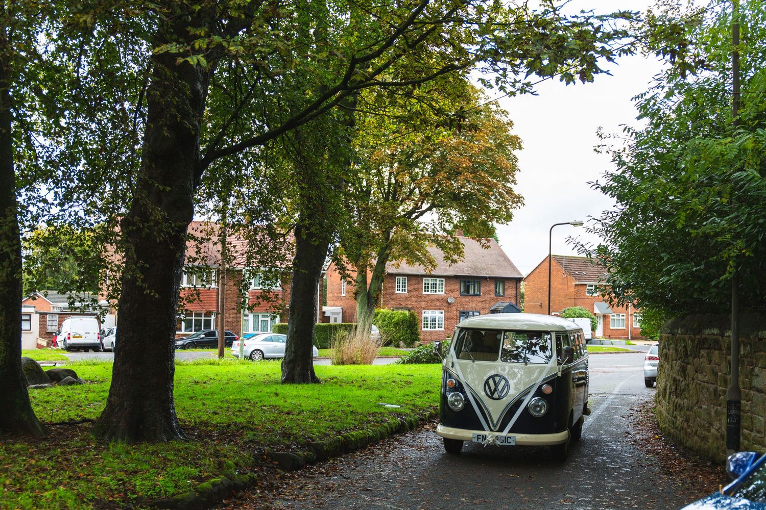 A vintage Volkswagen bus parked on a tree-lined street creates a nostalgic scene.