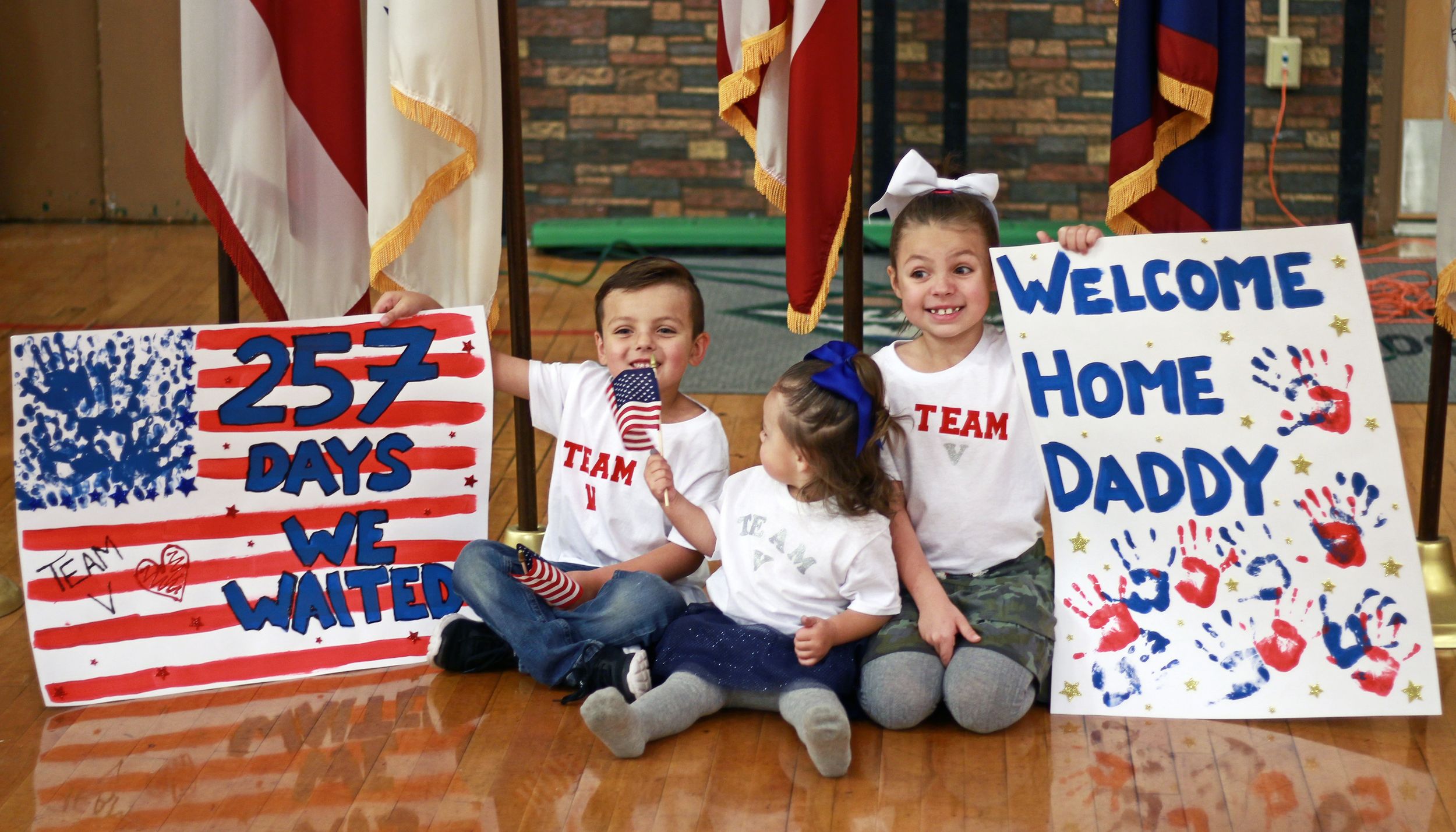 Young children holding heartwarming signs of love and welcome for a returning soldier, expressing their excitement