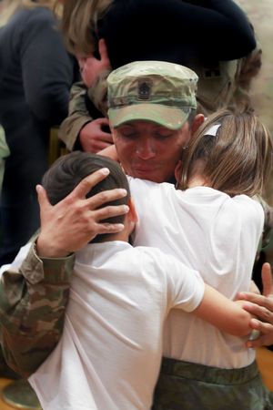 A father tenderly holding his children upon returning from deployment, a powerful reunion filled with love