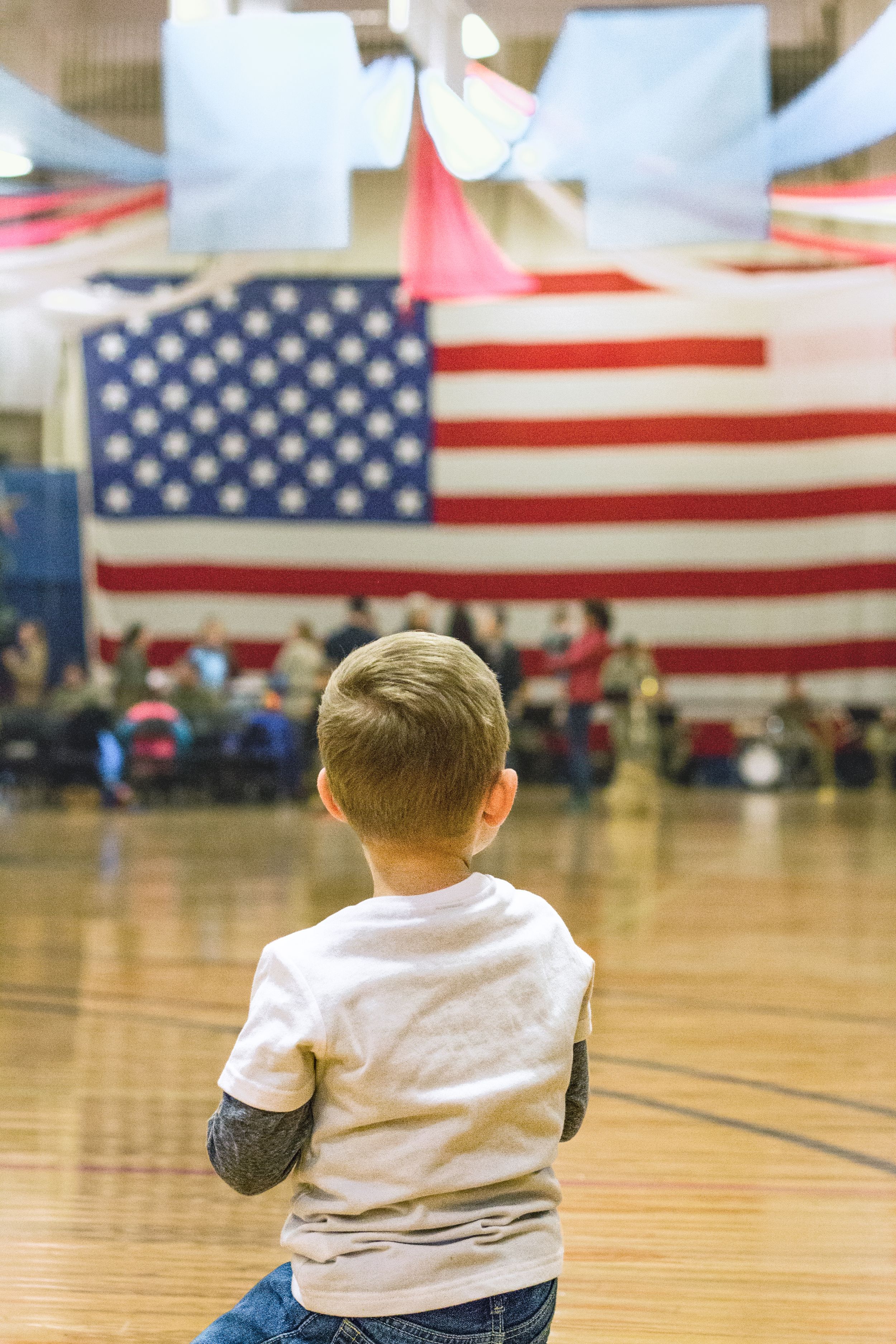 A young boy standing proudly in front of the American flag, symbolizing patriotism, hope, and the promise of the future.