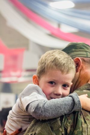 A father tenderly holding his son upon returning from deployment, a powerful reunion filled with love