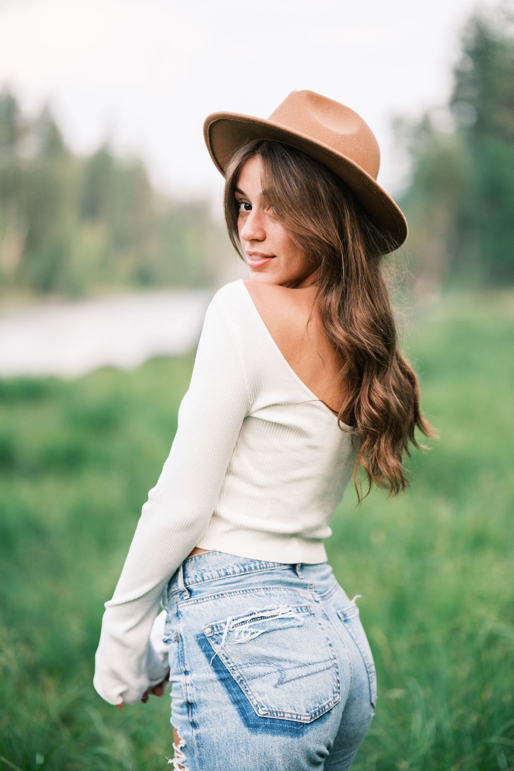 Country style portrait with brown hat and white sweater in natural setting.