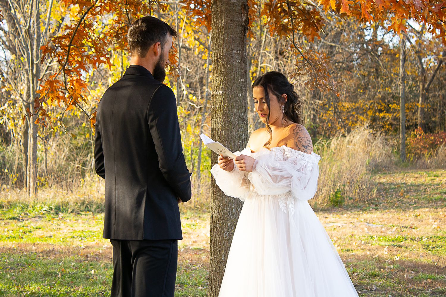 Bride and groom exchanging vows during fall outdoor ceremony.