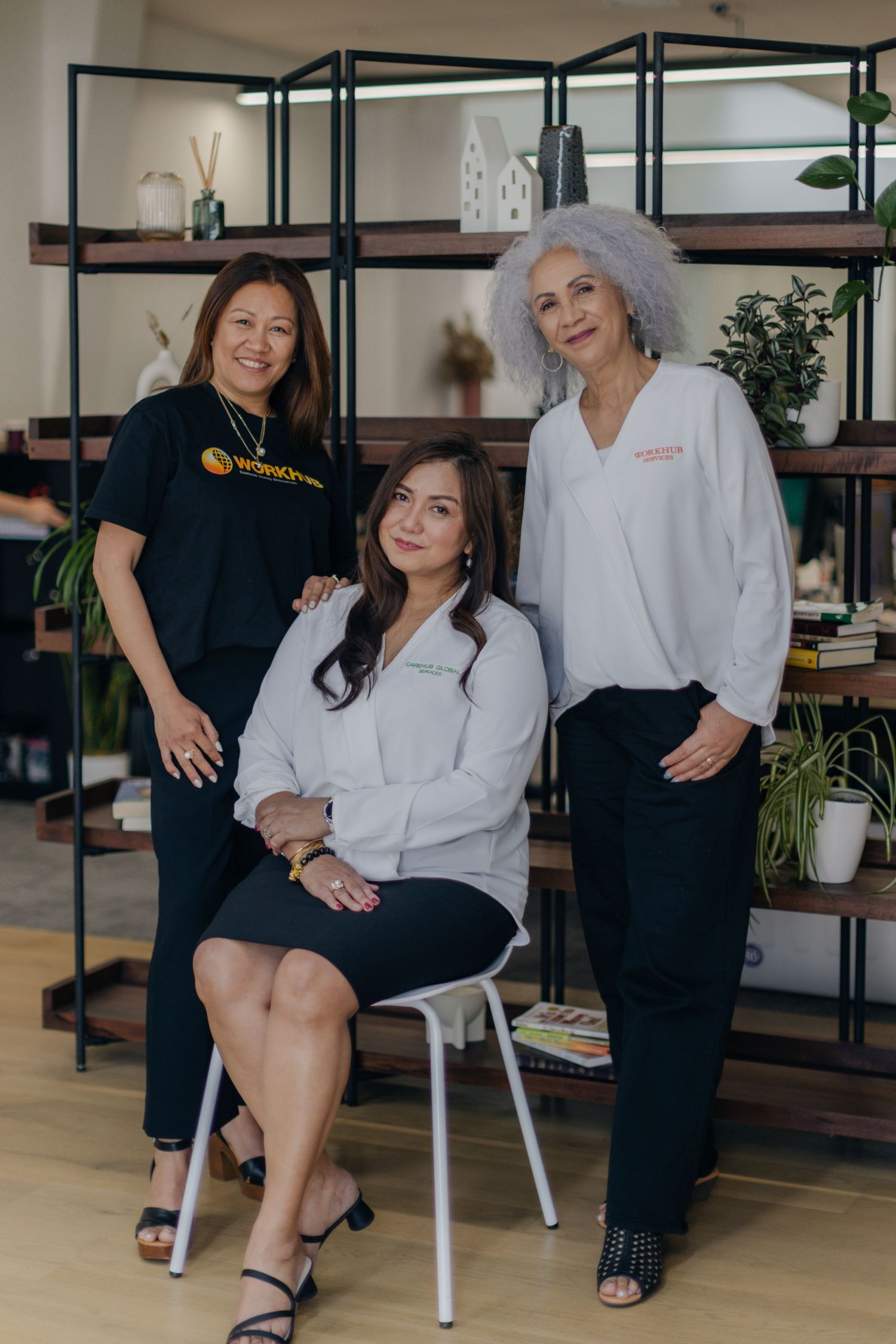Professional studio portraits showing two women in business attire posing together in a modern office setting.
