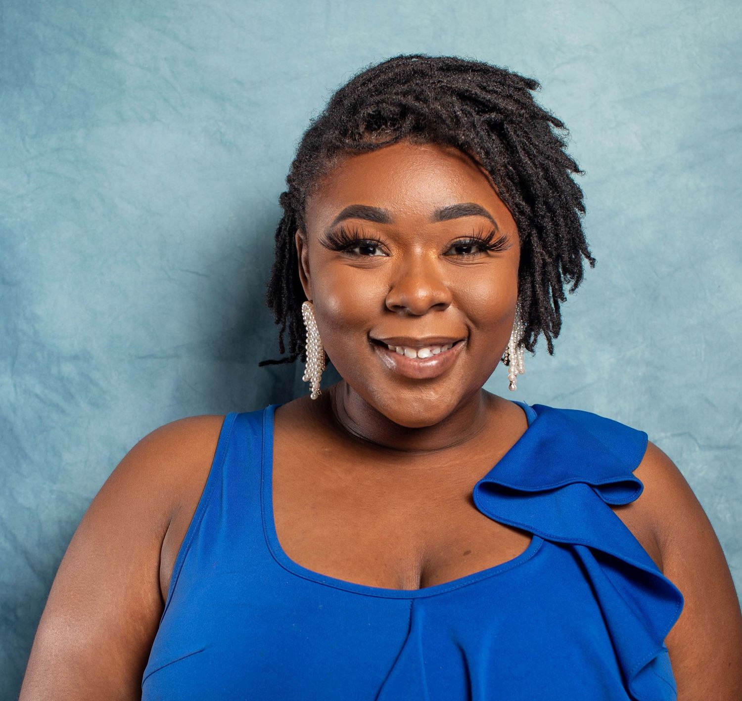 Portrait series in a blue dress against a light blue backdrop.