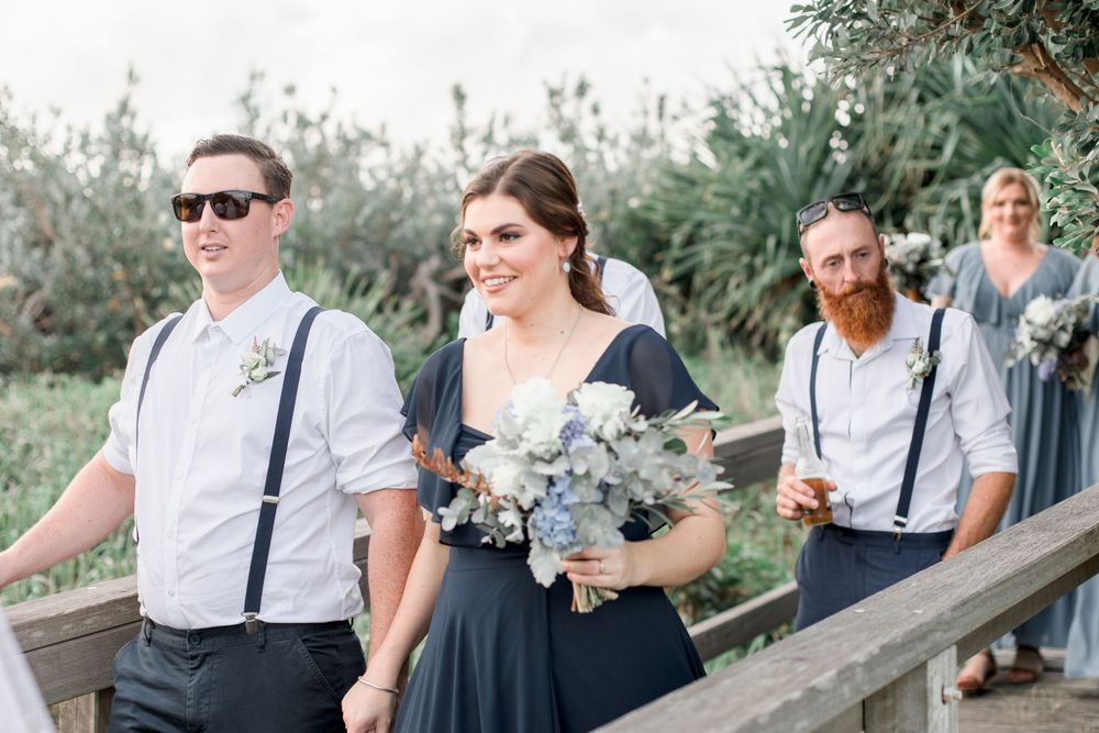 wedding party in shades of blue walking down pathway surrounded by australian native plants