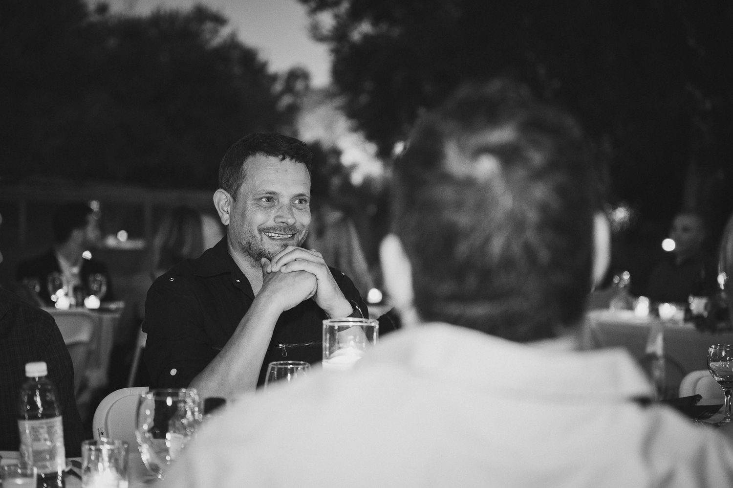 Black and white candid shot of guests dining at evening reception.