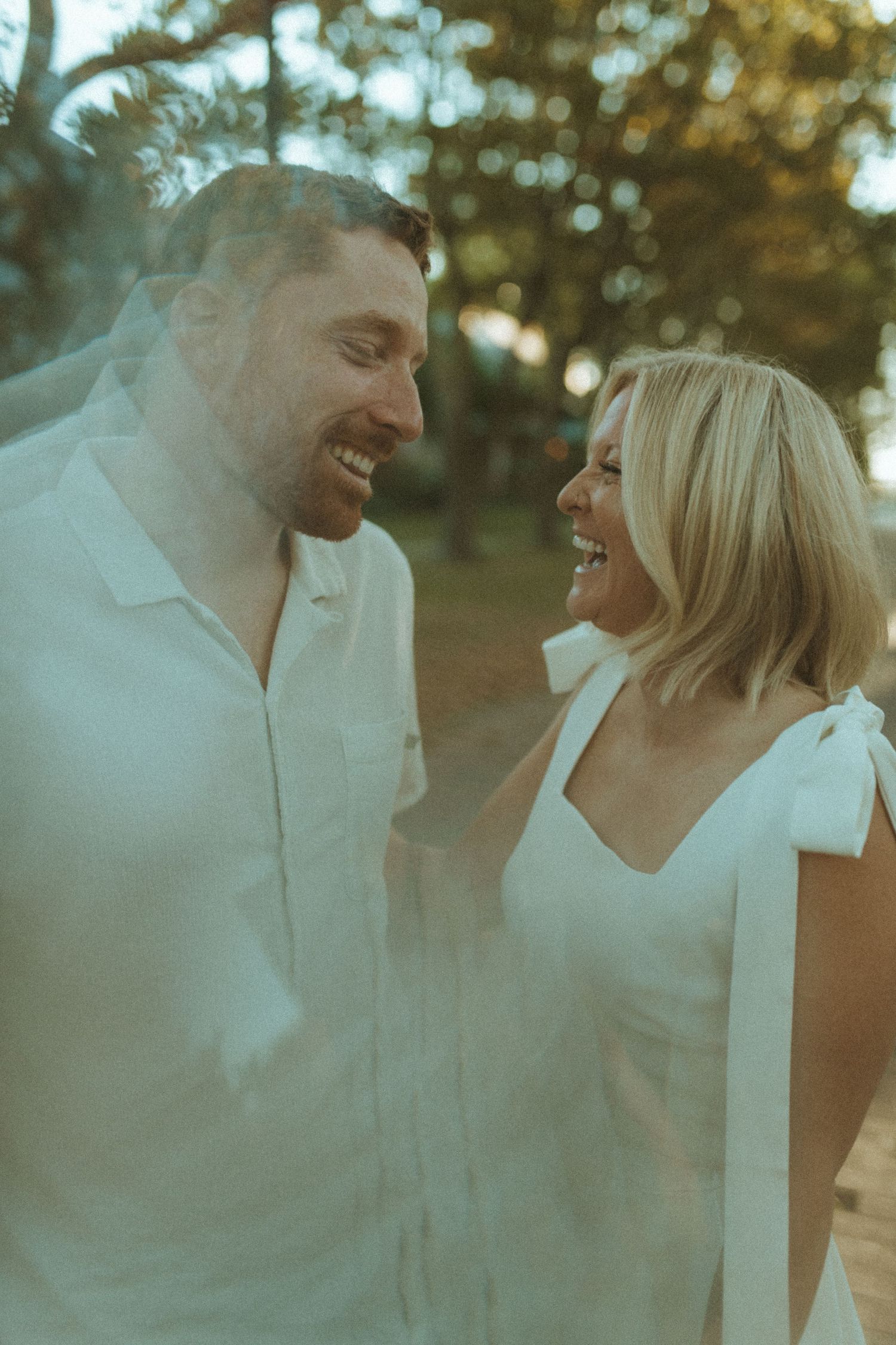 A couple shares genuine laughter during an intimate outdoor photo session.
