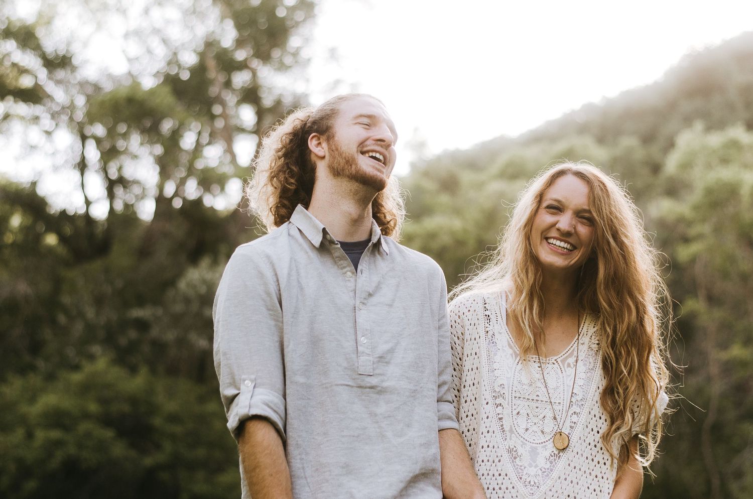Couple enjoying a candid moment together outdoors in warm evening light.