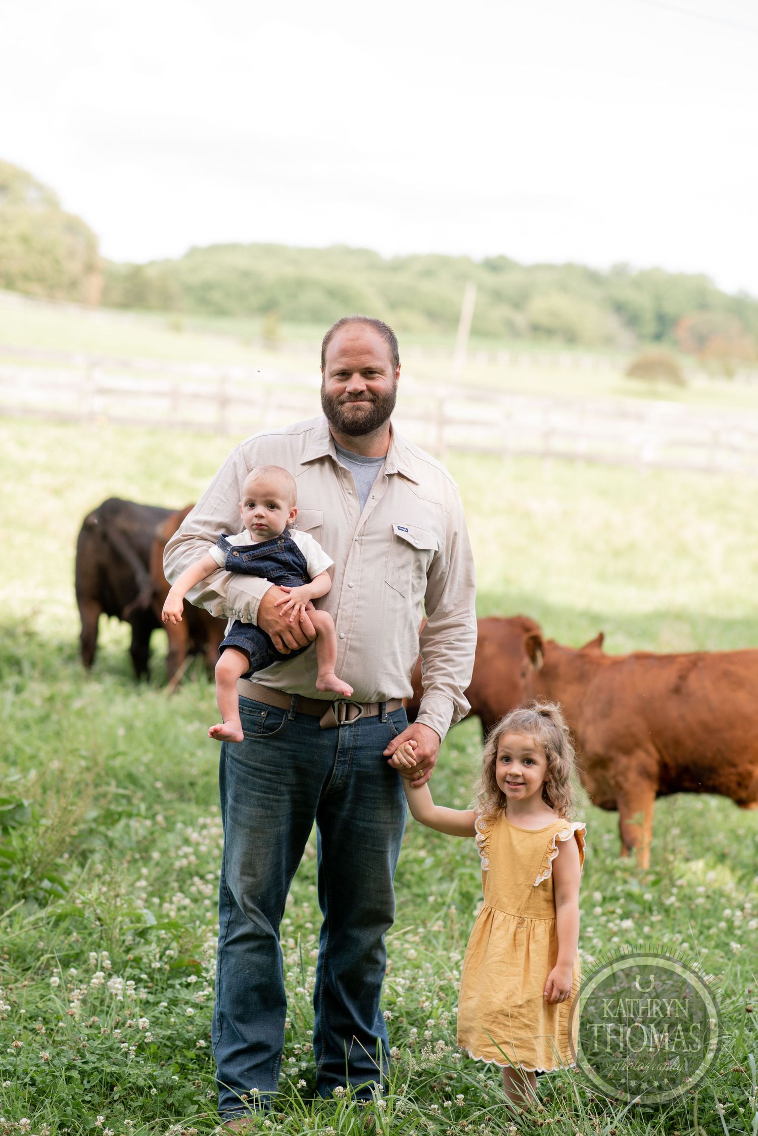 Family portrait on their farm with cattle grazing in the background.