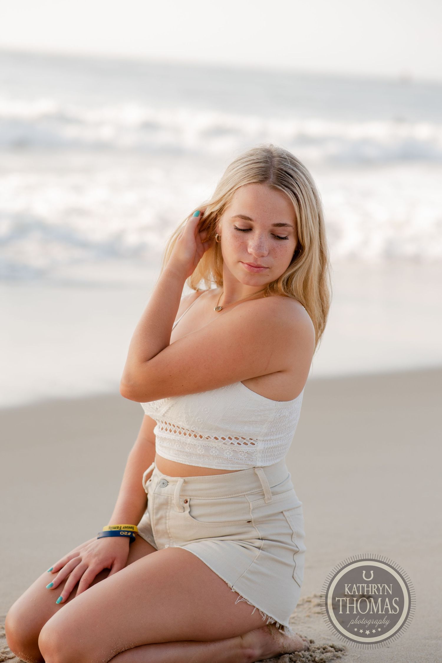 Portrait of a person in a white crop top and shorts posing at the beach during sunset.