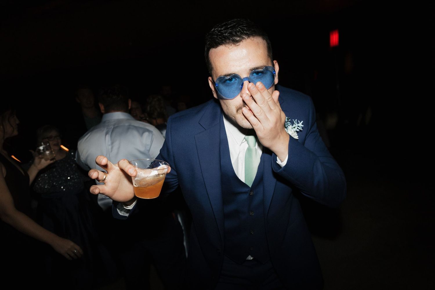 A guest in a navy suit strikes a pose on the dark dance floor.