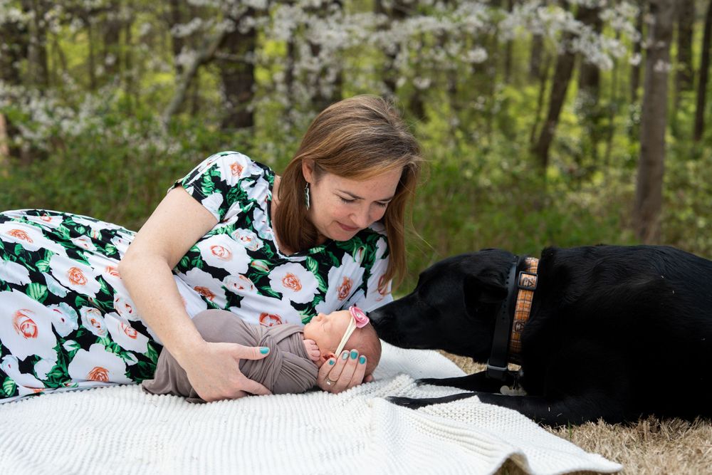 A Lisa Liberati Photography newborn photo of a mom and a baby laying on the ground.