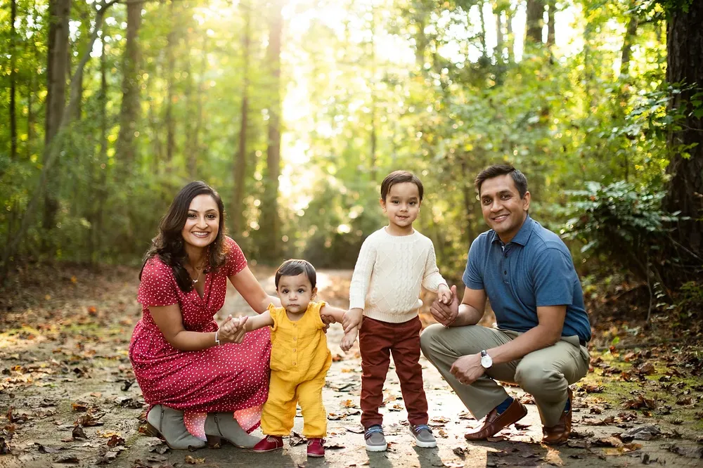 A family of four at a park with seasonally fall leaves