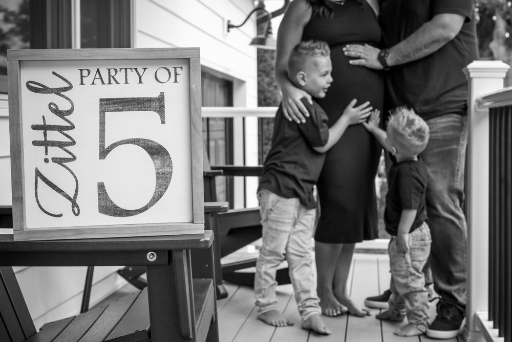Family members gather around a 'Party of 5' sign on a front porch.
