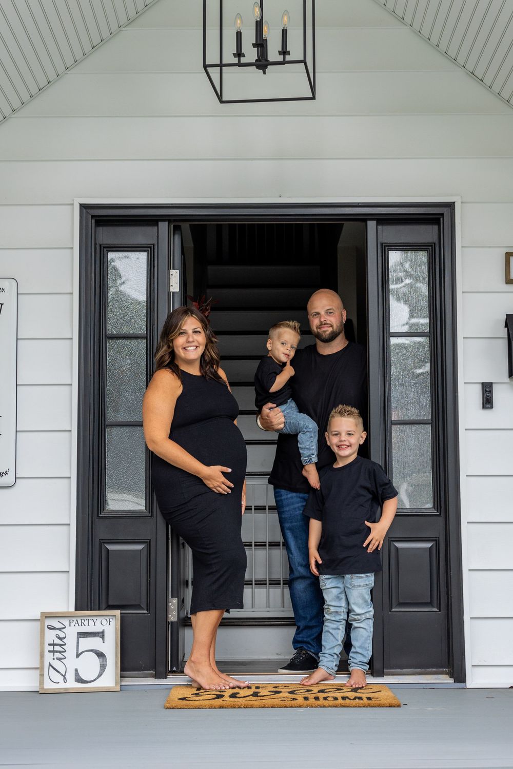 A family stands together in the entrance of their modern farmhouse-style home.