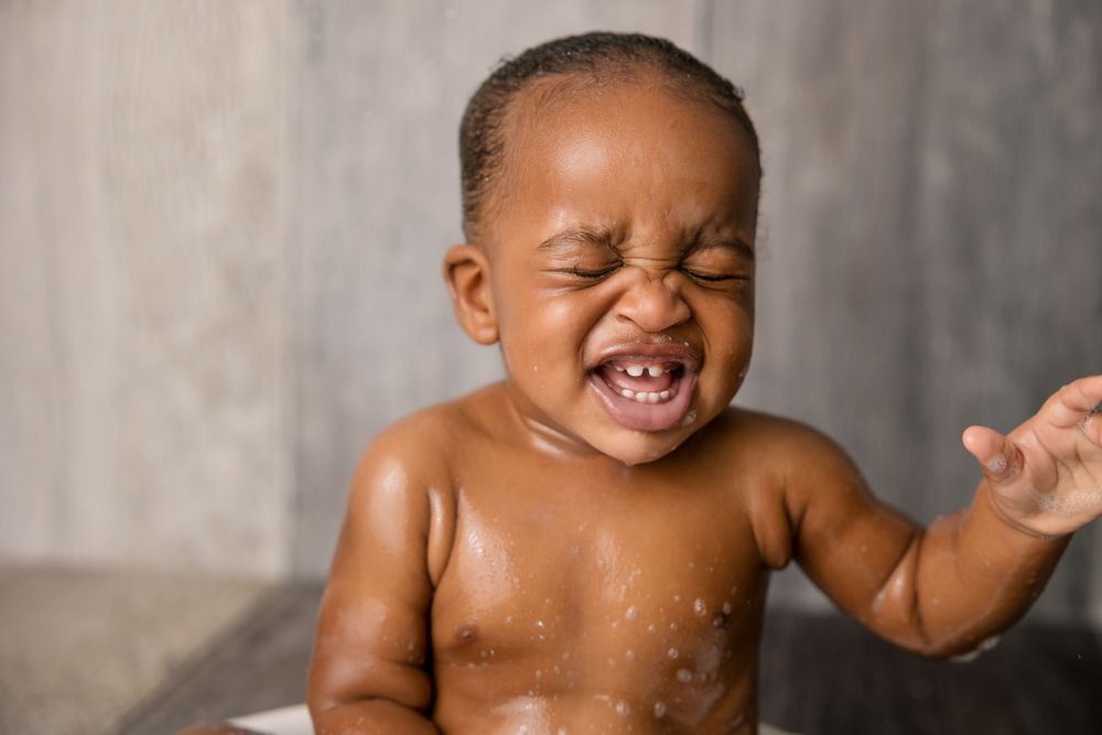 Pure joy captured as water droplets splash around a laughing baby during bath time.