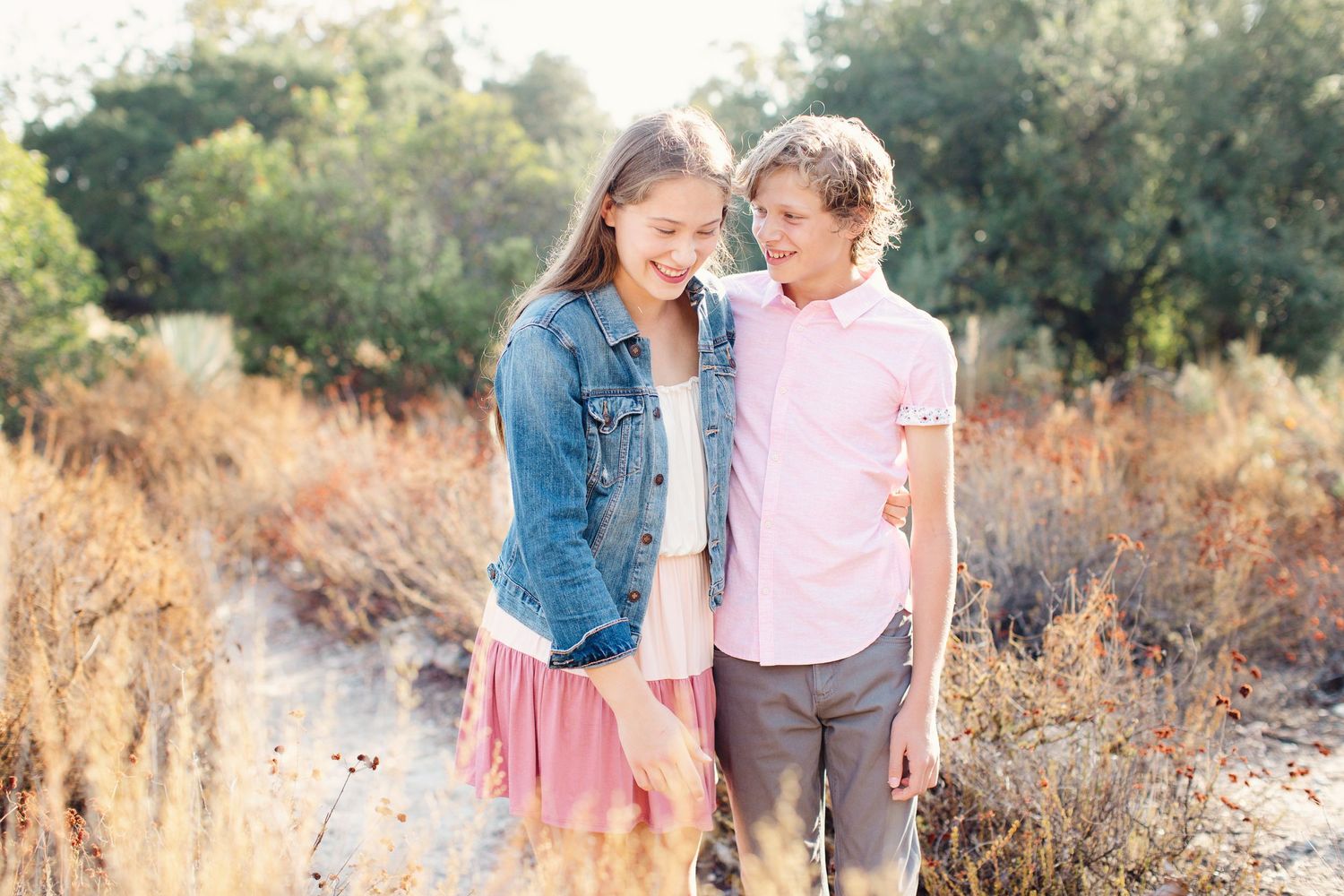 Two young people sharing a sweet moment together on a sunny outdoor trail.