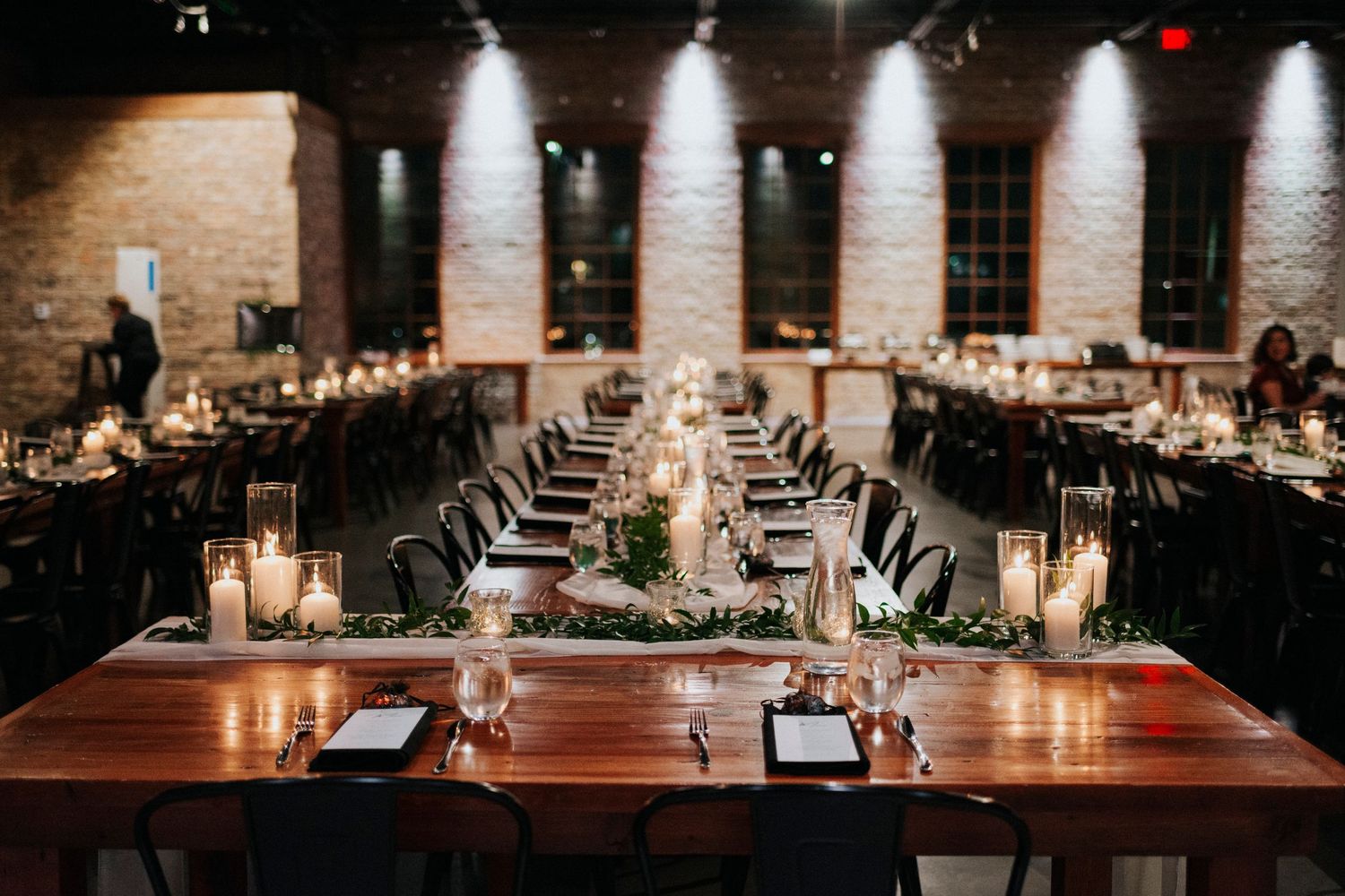 Dark and moody view of dinning hall from head table at a wedding reception.