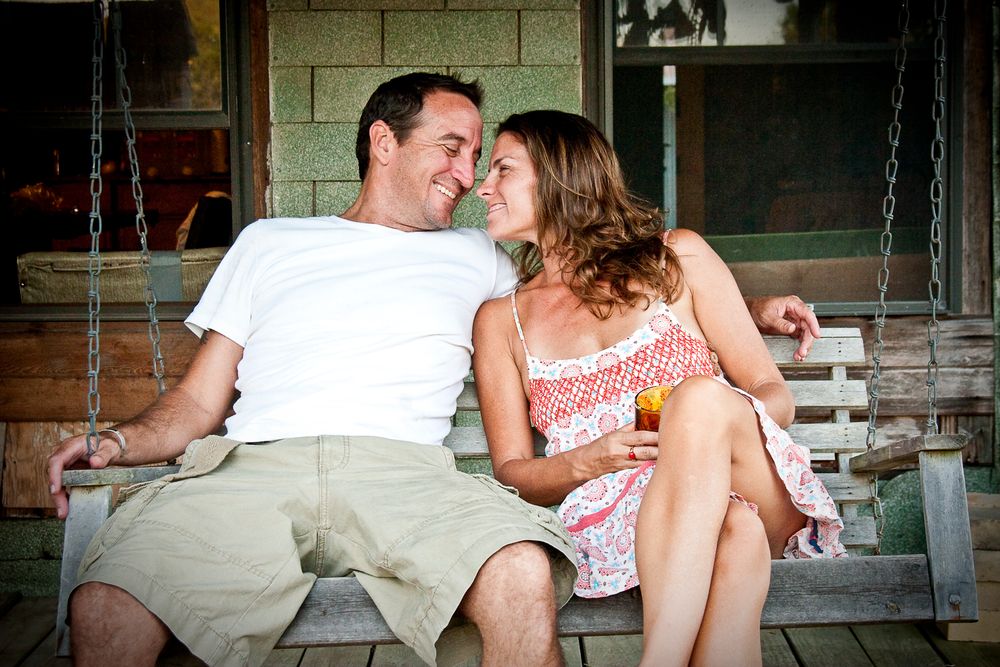 A couple sitting close together on a porch swing share an intimate moment.
