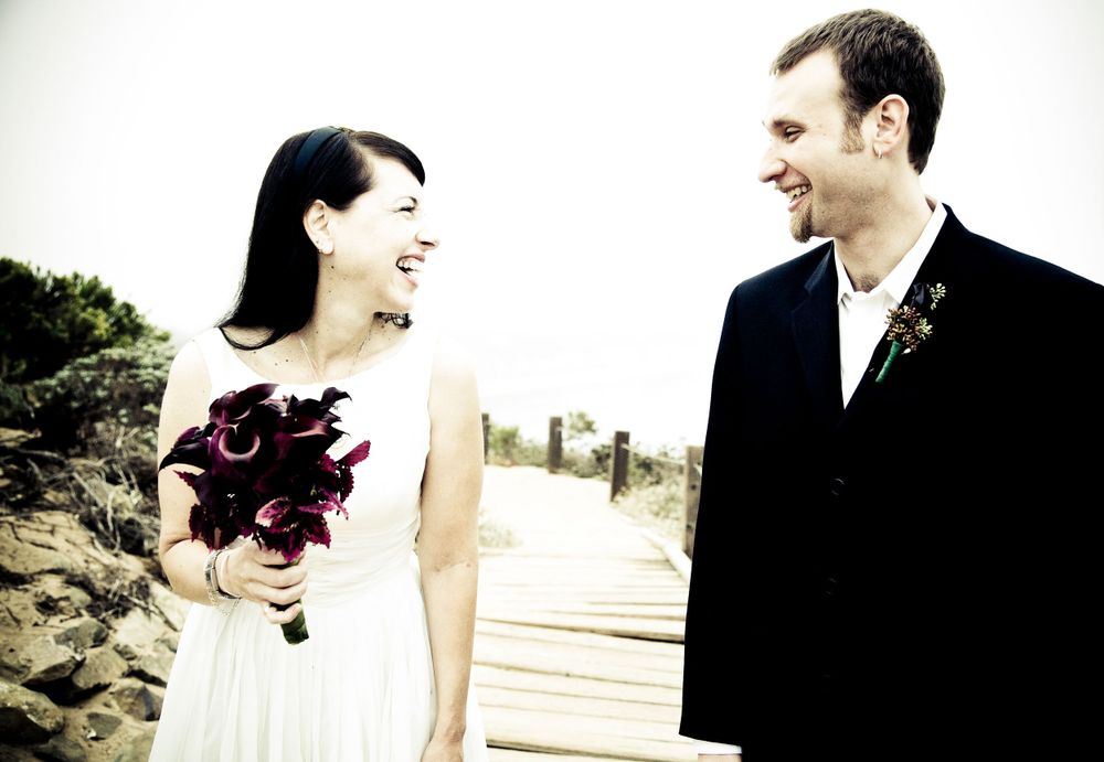 Couple in wedding attire sharing a joyful moment outdoors.