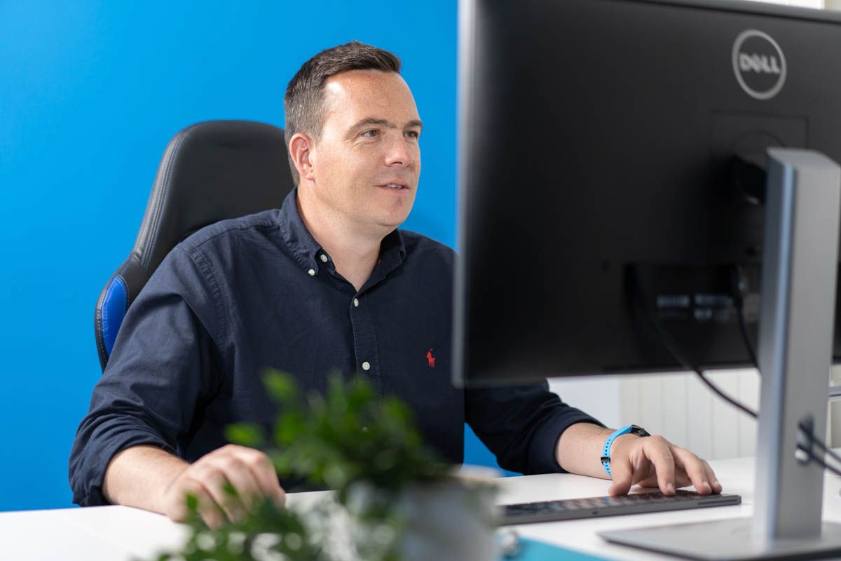 Professional working at desk with Dell monitor in modern office environment.