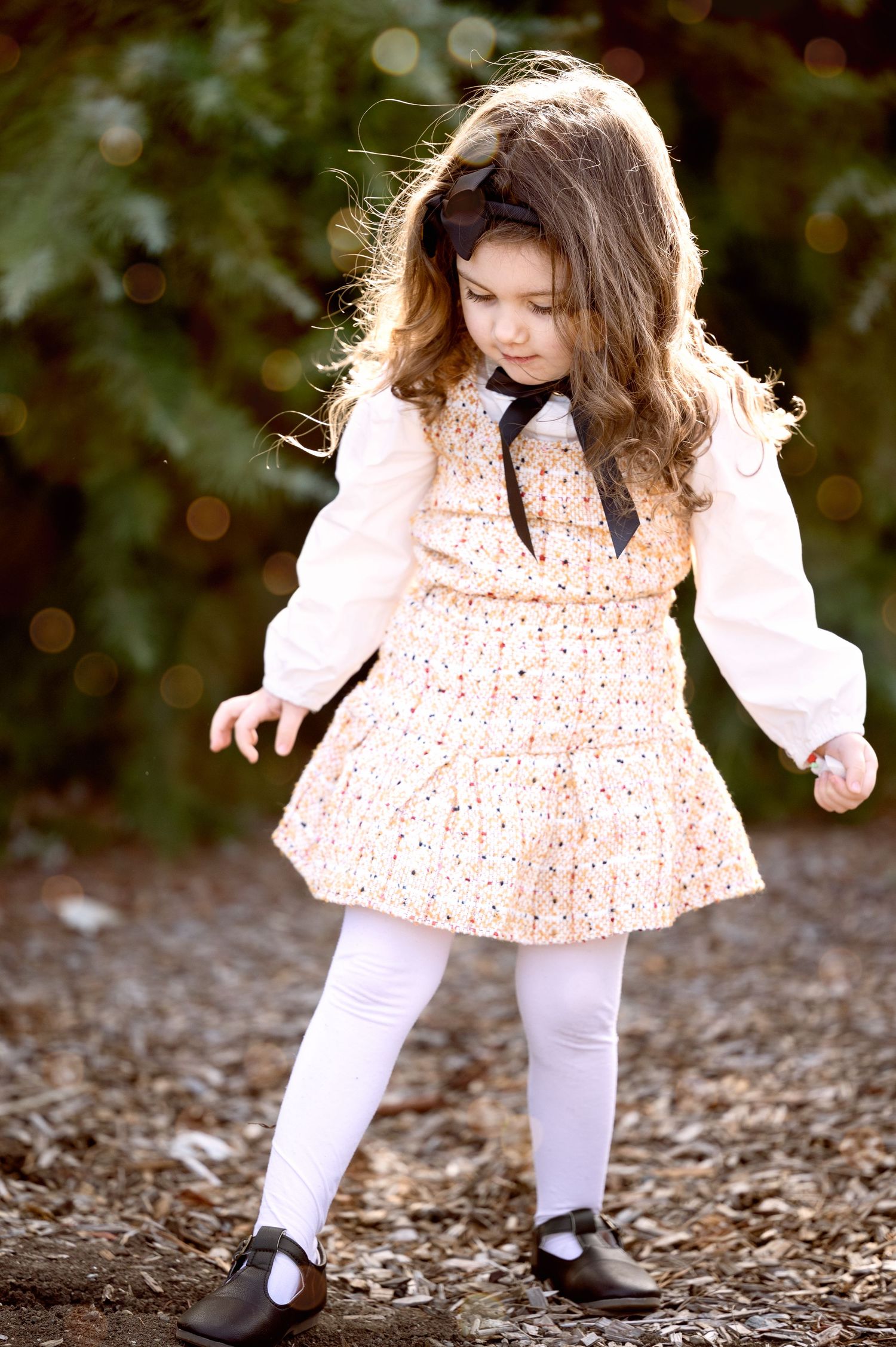 Little one in peach polka dot dress and white tights twirling outdoors.