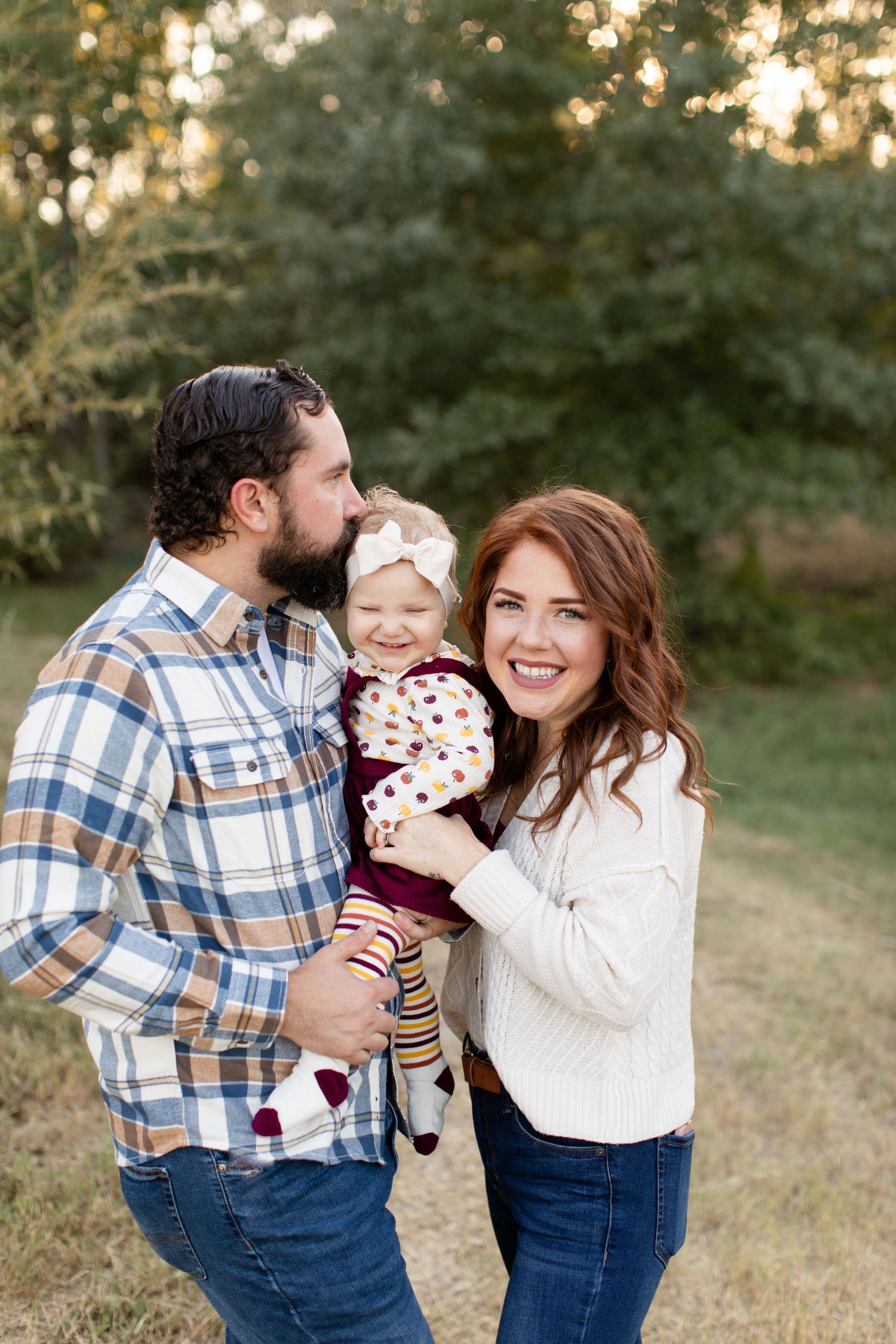 A family of three shares an intimate moment together during outdoor autumn photoshoot.