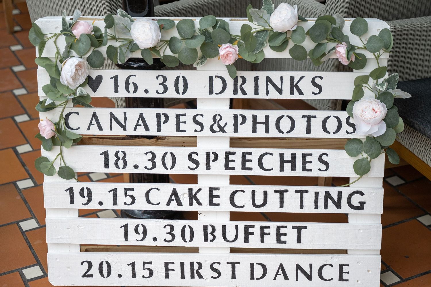 Vintage-style wedding timeline sign listing events from drinks through first dance.