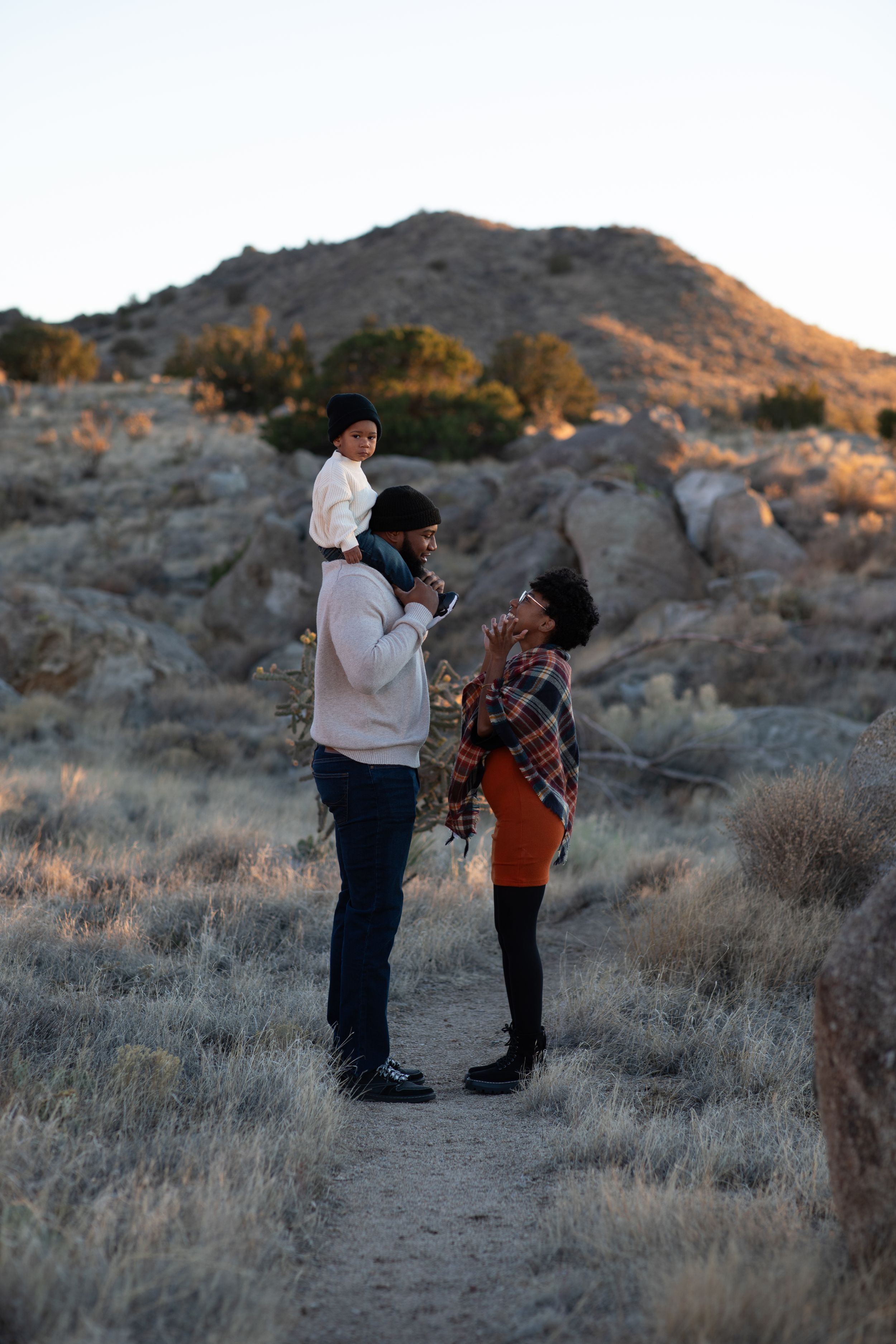 Family moment captured on desert trail with mountain backdrop at golden hour.