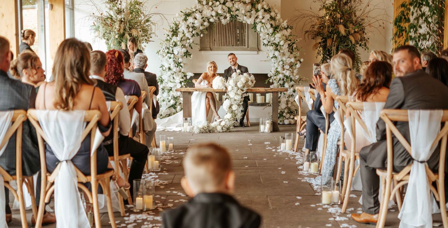 Bride and Groom sat at the altar looking at the family and friends