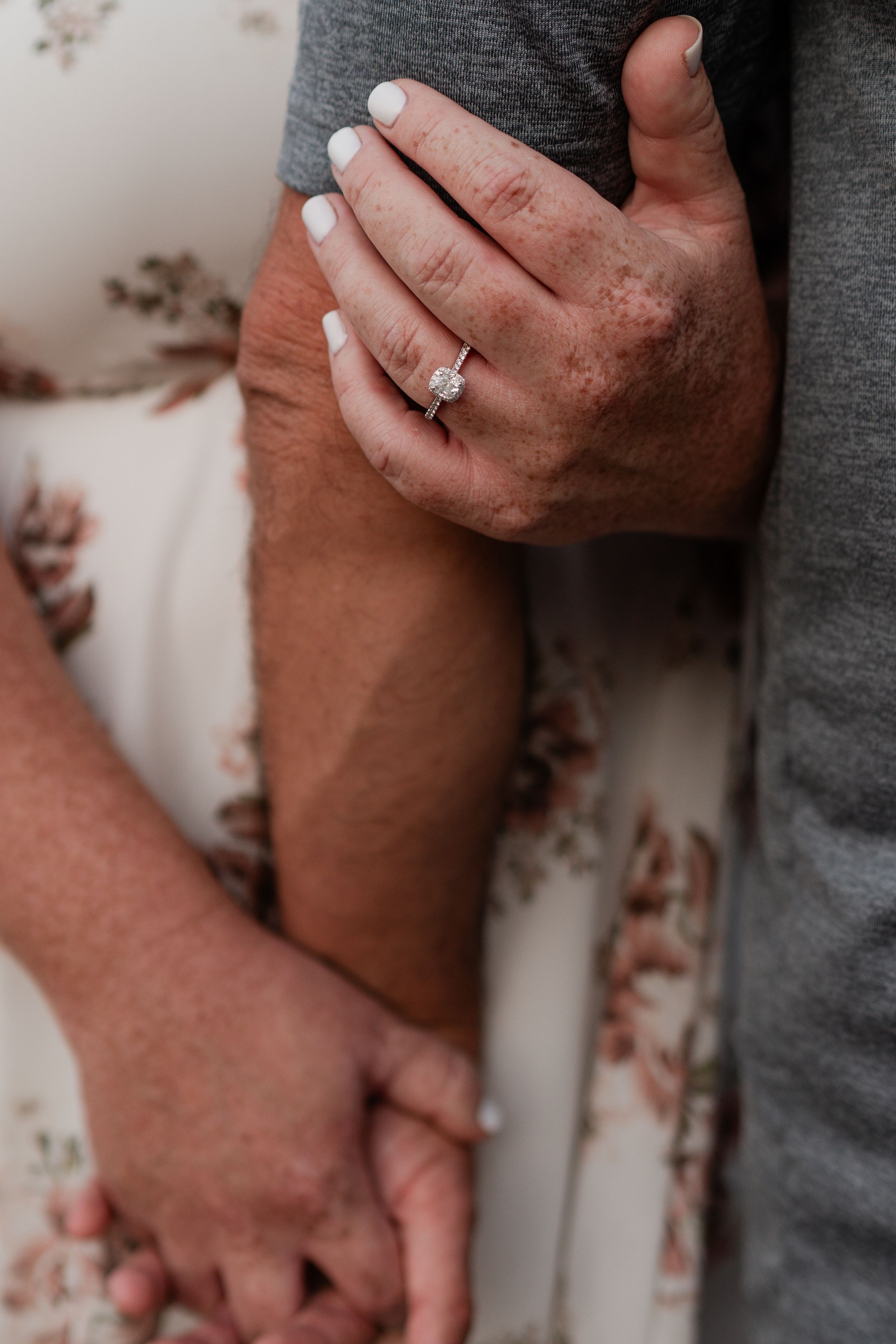 Close-up of intertwined hands with an engagement ring showing affection and commitment.