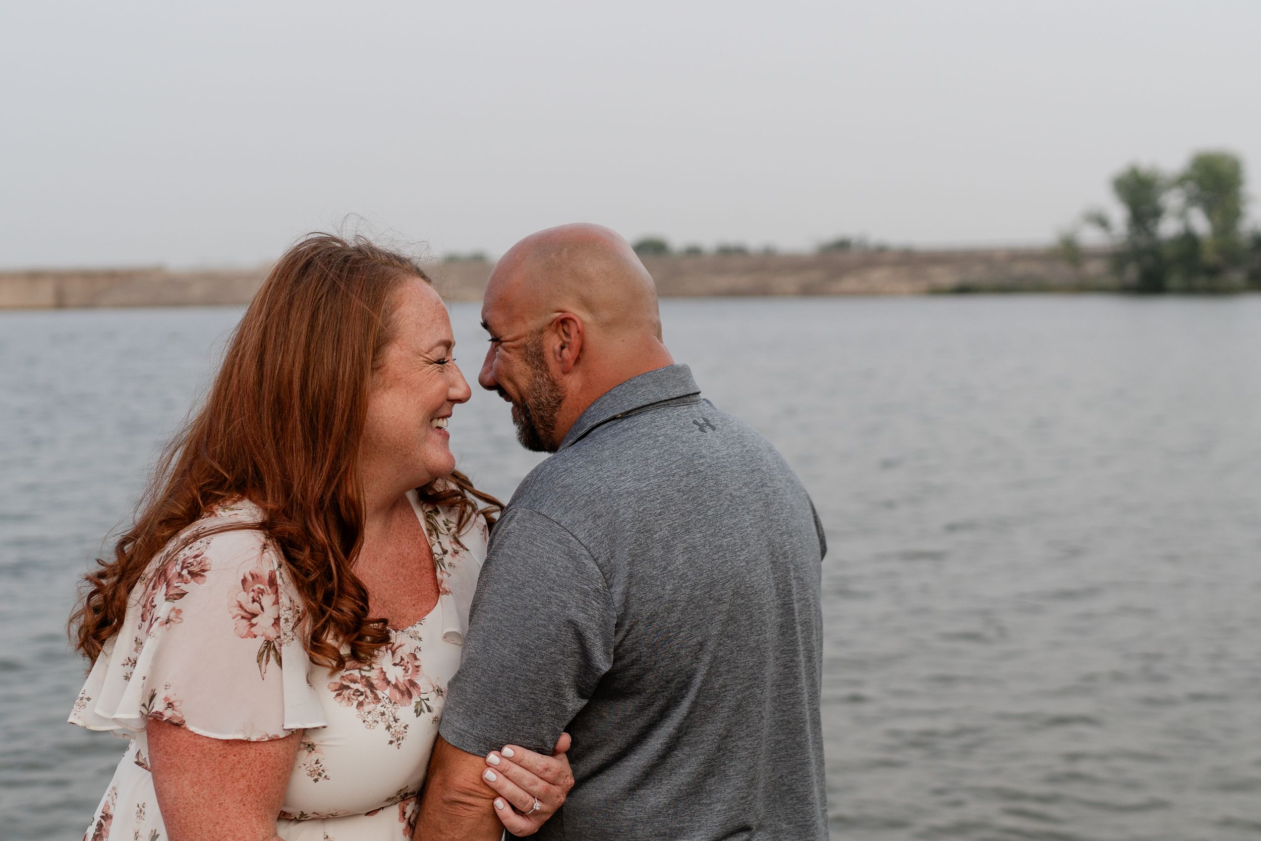 Happy couple embracing by the lake during outdoor photoshoot.
