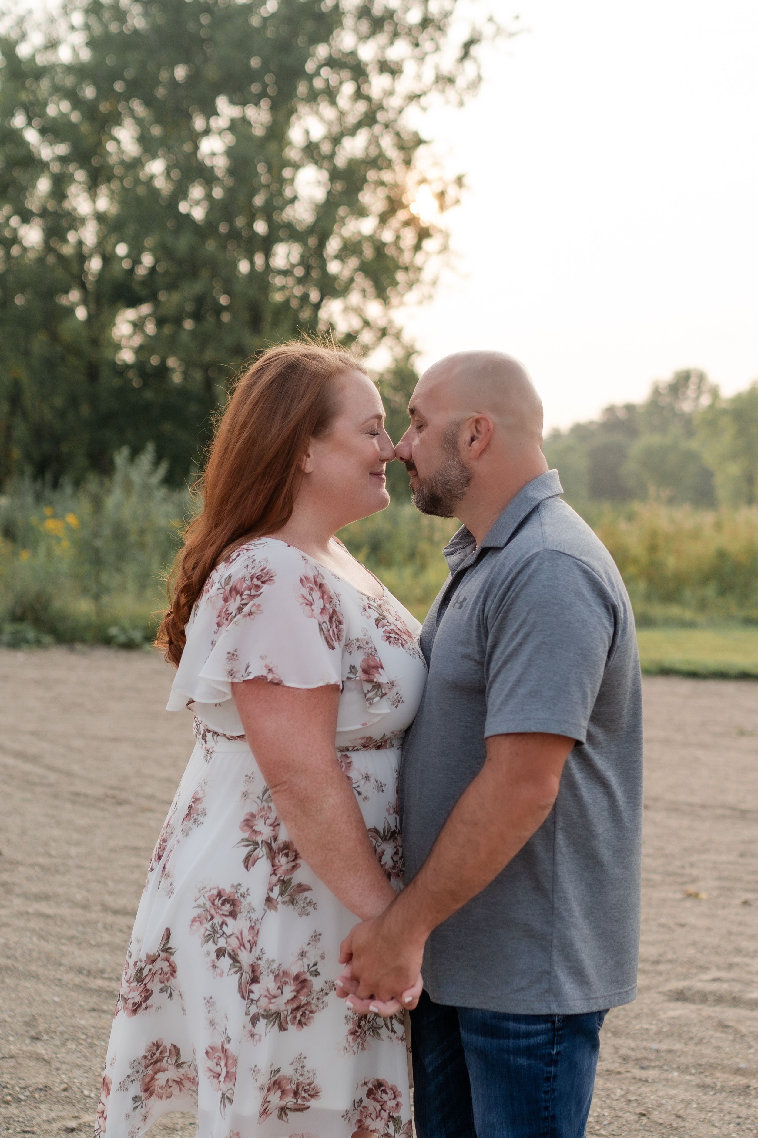 Couple holding hands and smiling during outdoor engagement photoshoot.
