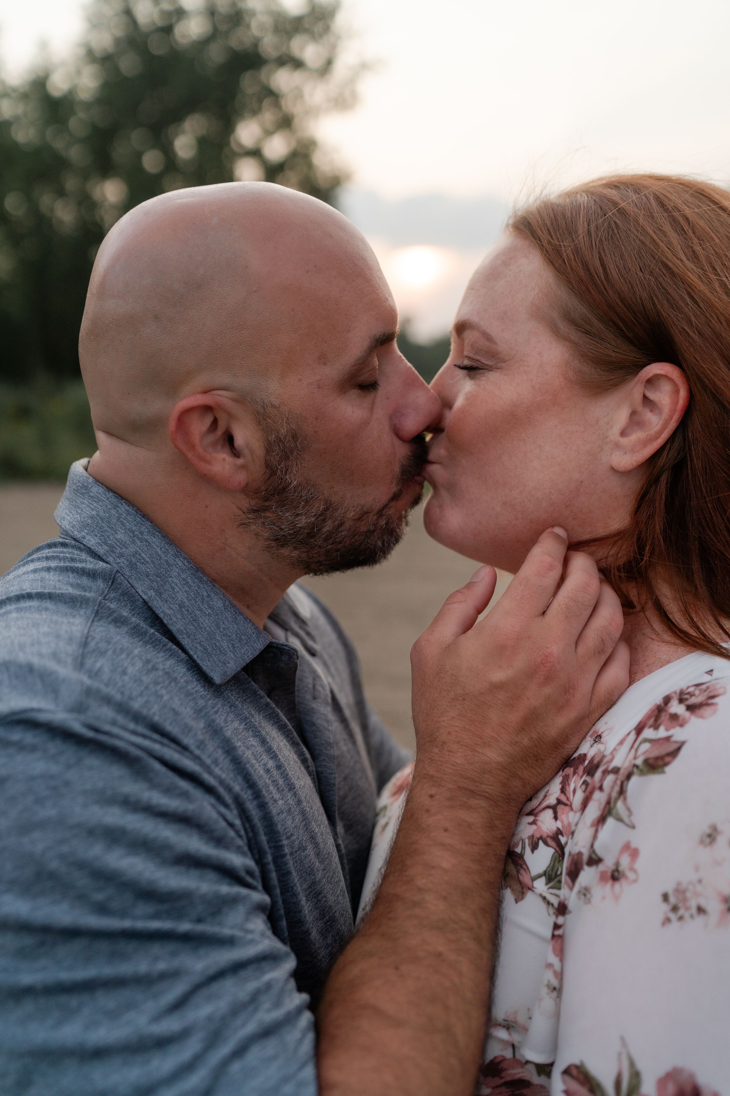Romantic sunset portrait of couple sharing passionate kiss outdoors.