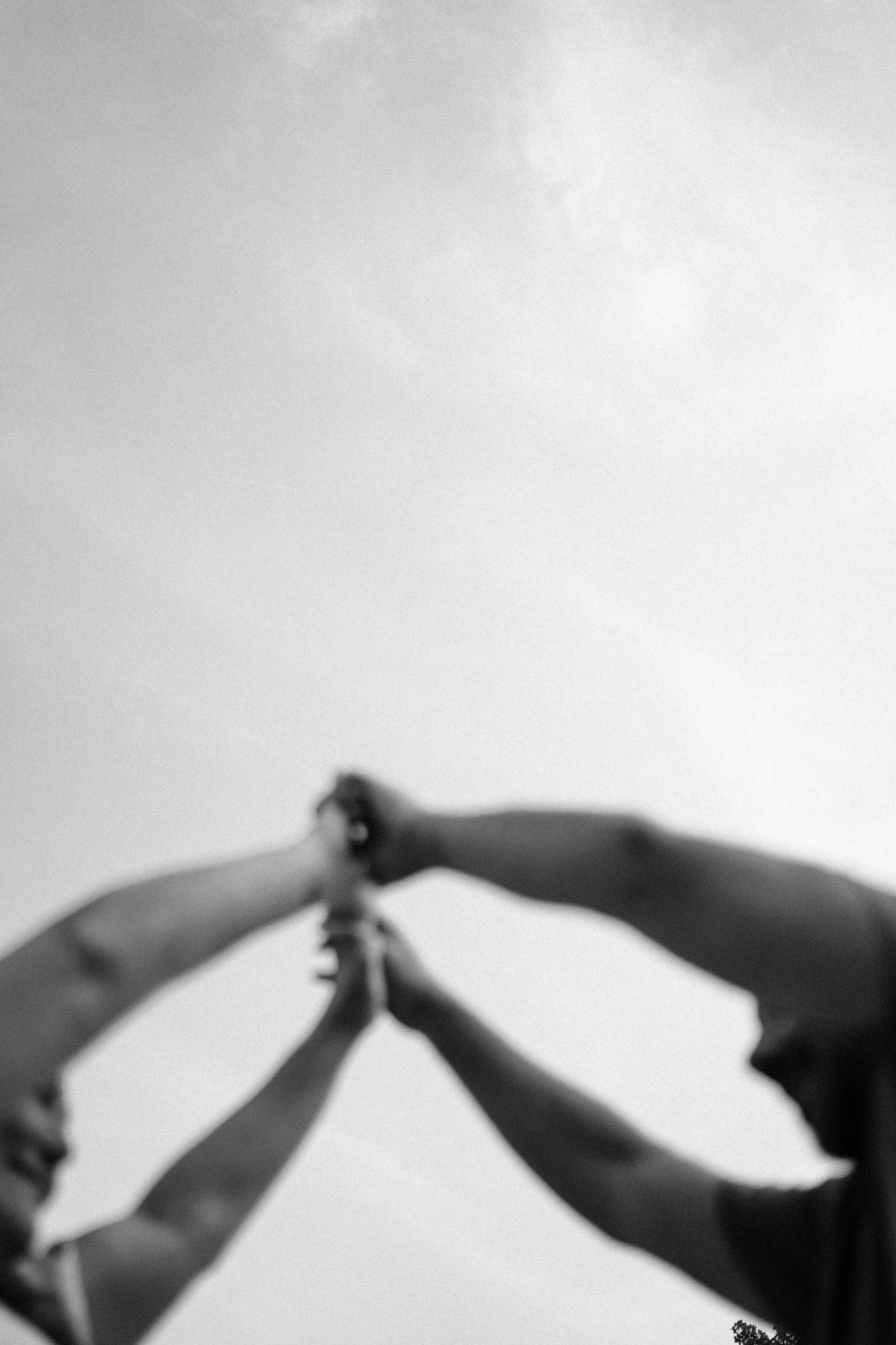 Silhouetted hands joining together against bright sky.