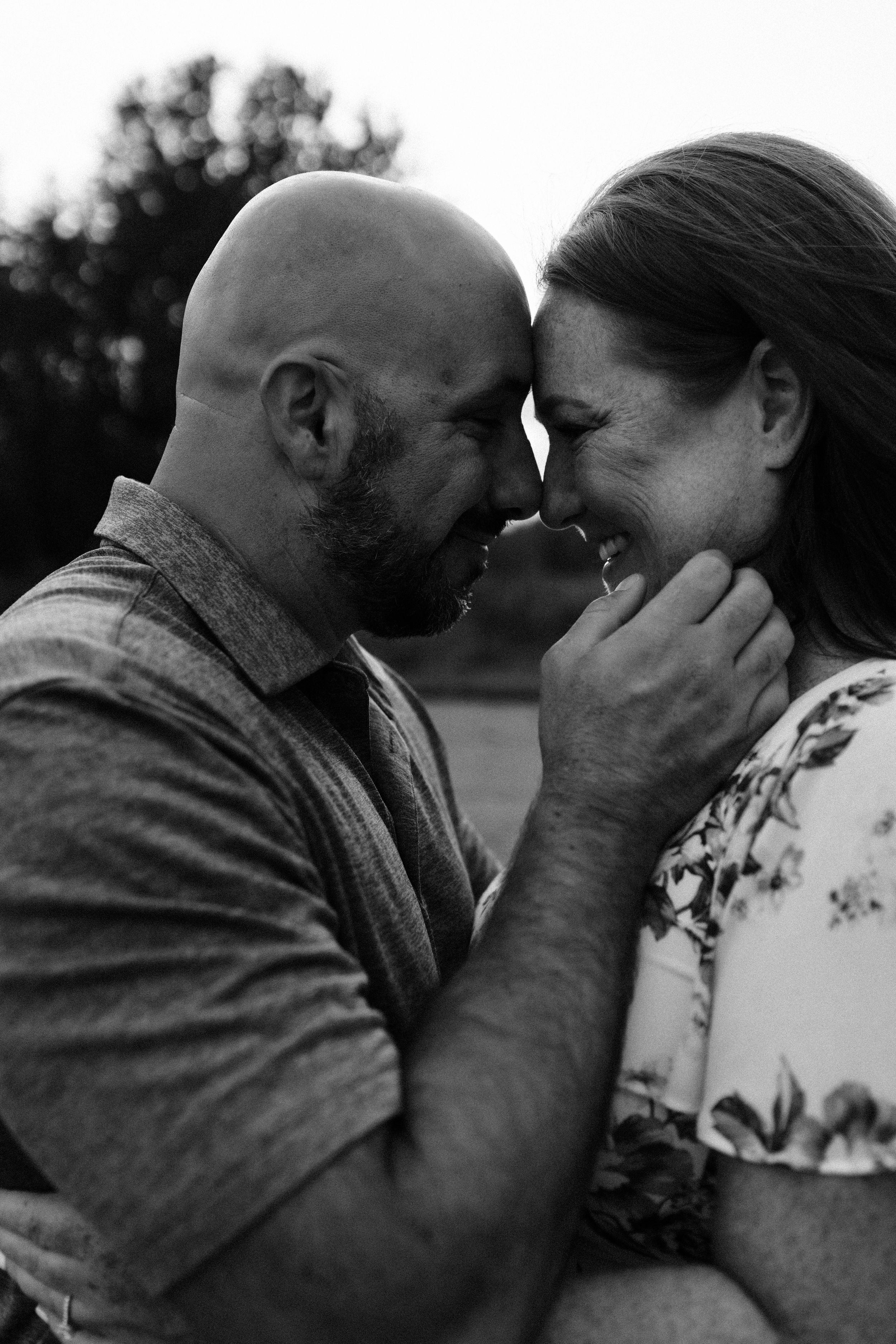 Intimate black and white portrait of couple sharing tender moment outdoors.