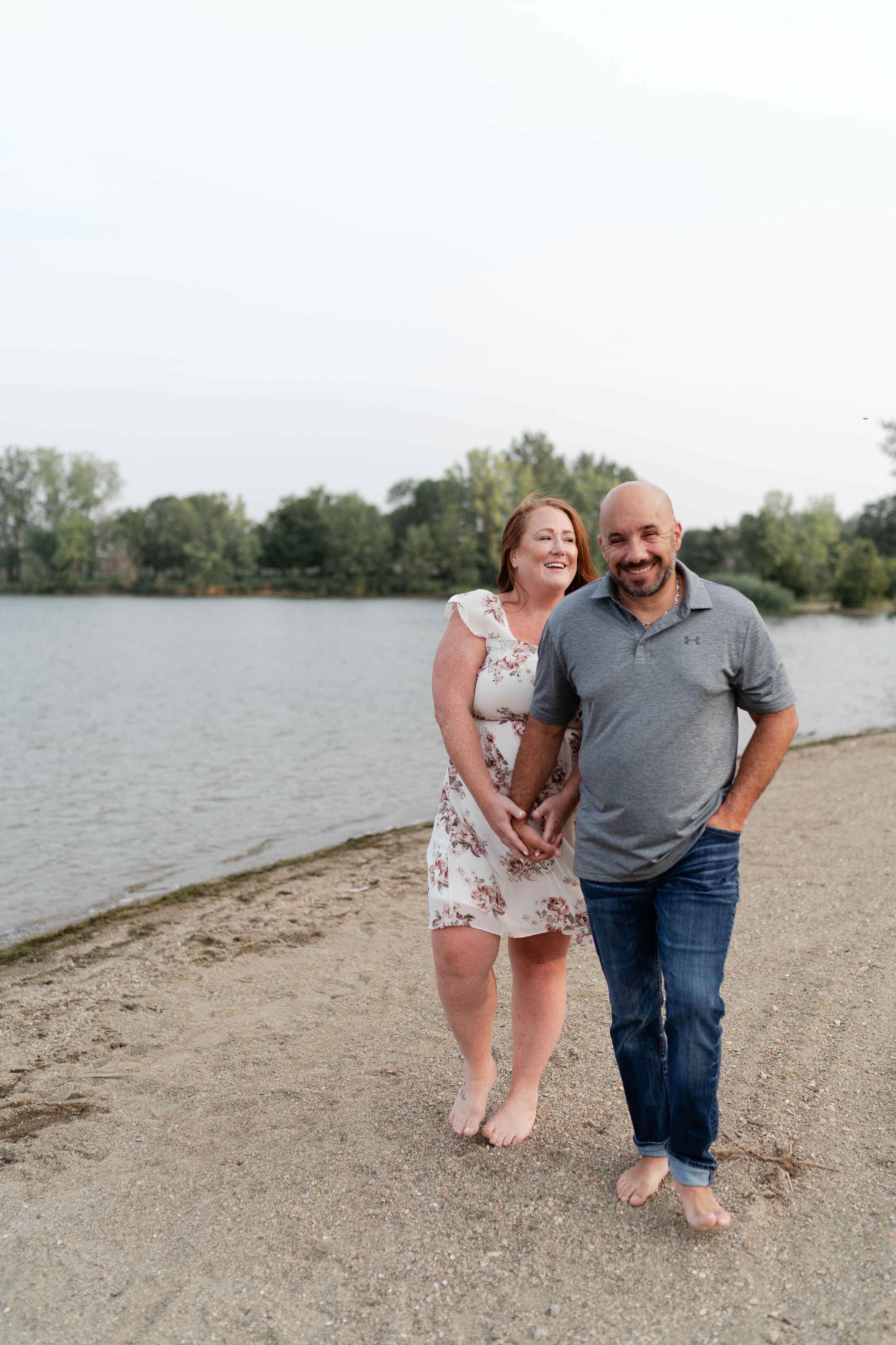 A happy couple embracing on a beach trail beside a peaceful lake.