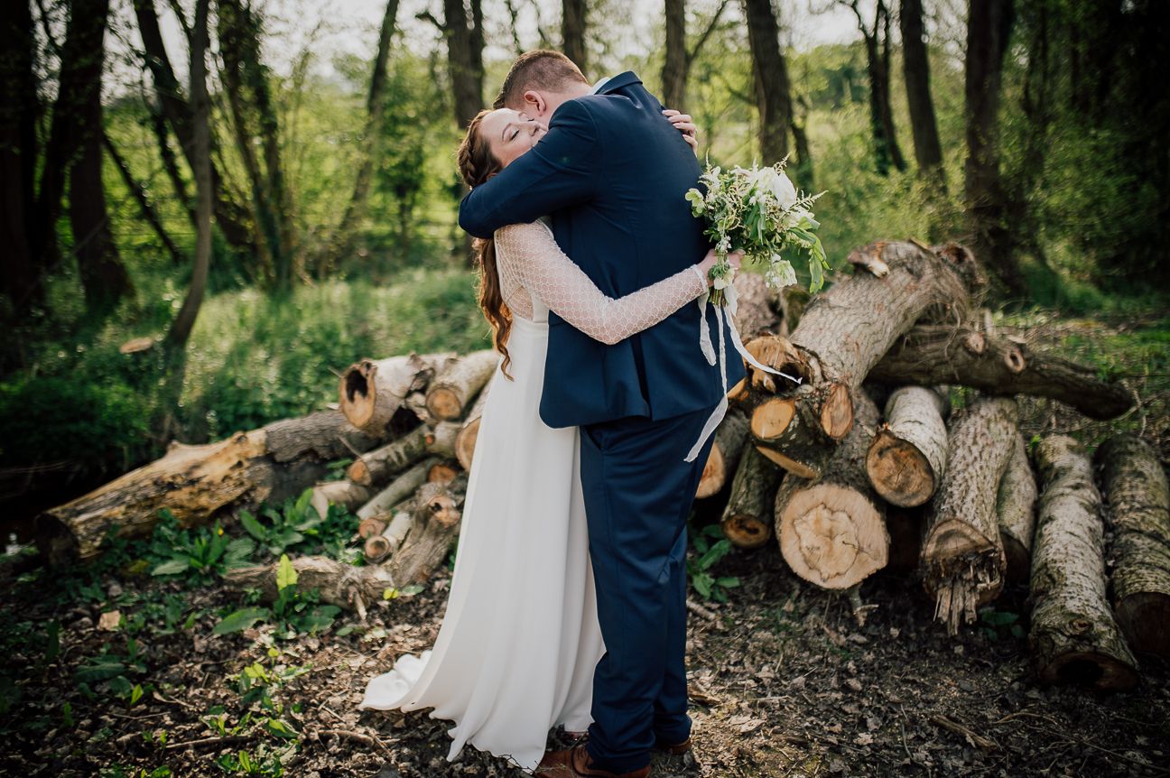 Series of woodland wedding photos with a couple posing near stacked logs. Worcestershire Wedding photographer.