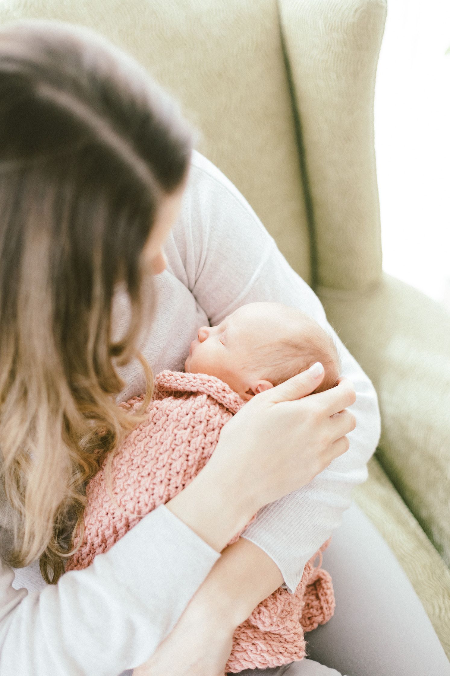 Close-up view of infant wrapped in pink knit blanket during feeding time.