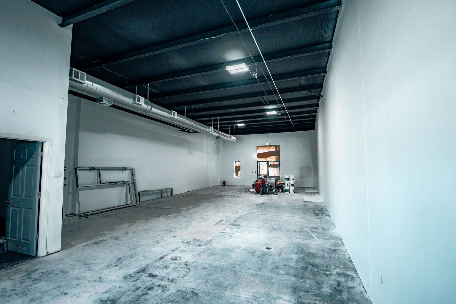 Empty industrial space with exposed ceiling and concrete floor shows renovation potential.